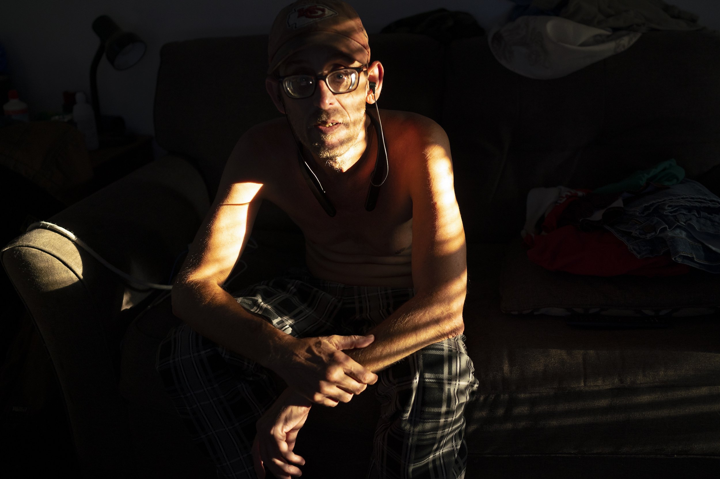  Daryel Franklin Miller, 50, watches television the morning after sleeping on the couch at his father's home in Excelsior Springs, Missouri, on September 20, 2022. After years of traumatic life experiences, including losing his older sister to accide