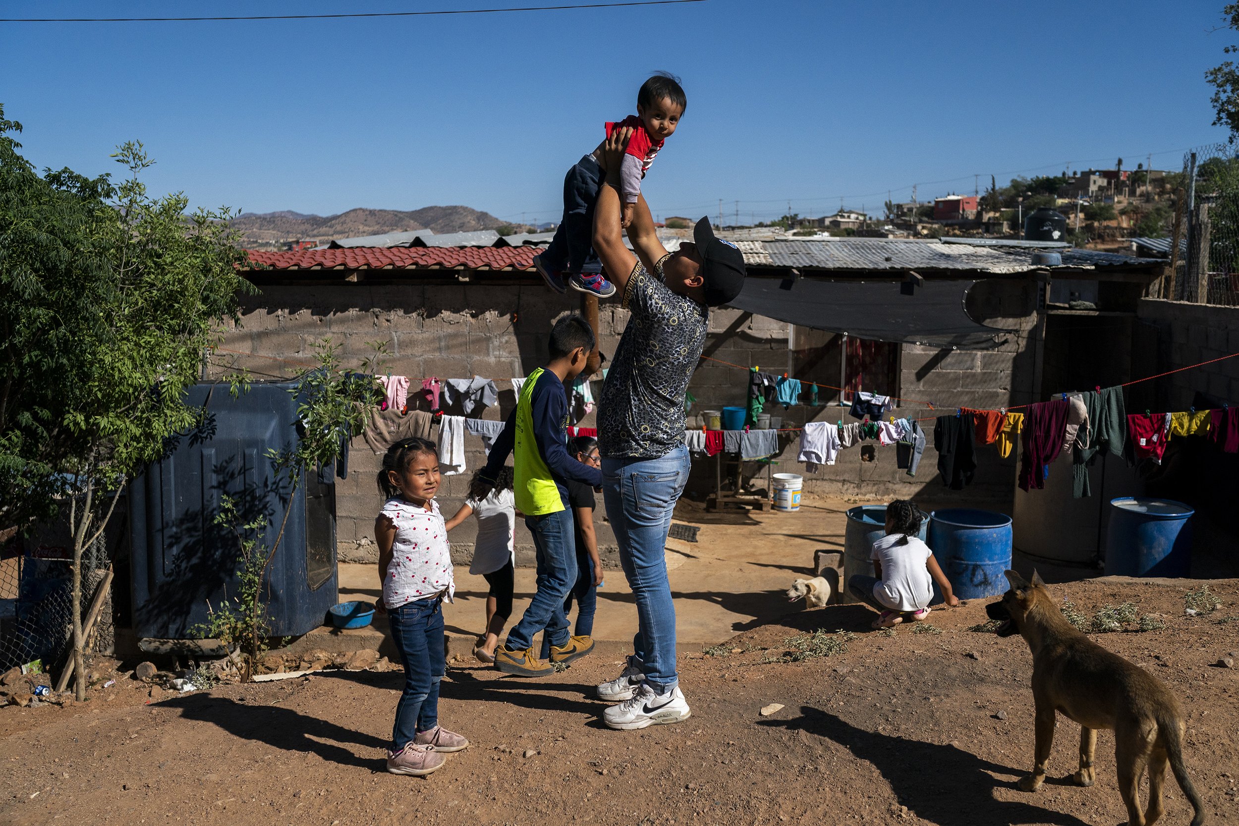  Rafael Delgado, center, holds up his baby Liam Delgado Garca, 1, outside their home on the outskirts of Nogales on Monday, May 23, 2022, in Nogales, Mexico. Rafael moved to Nogales to apply for asylum after his brother Carlos was kidnaped by the ca