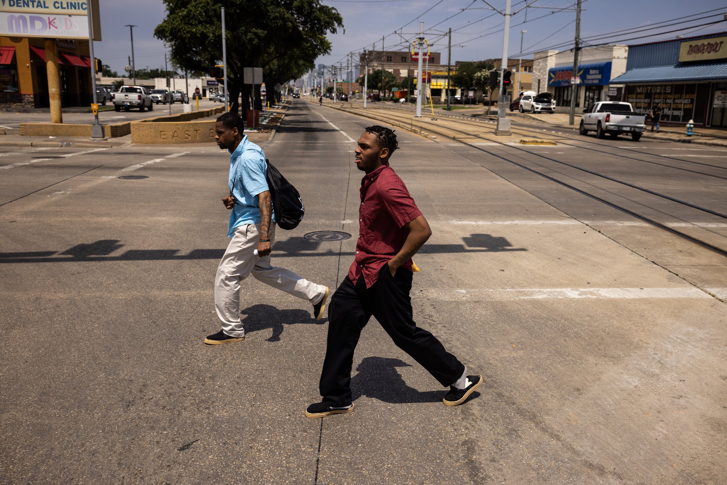  Stephan Pantallion, along with another a friend from jail, cross the street, Friday, May 10, 2024, in Houston. Pantallion refused the invitation from other people to jaywalk across the street out of fear of violating parole. “I just don’t want troub