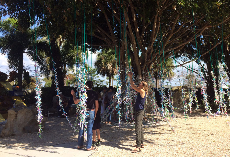 Wishful thinking. Juli and other visitors add wishes to the ficus tree outside the museum.