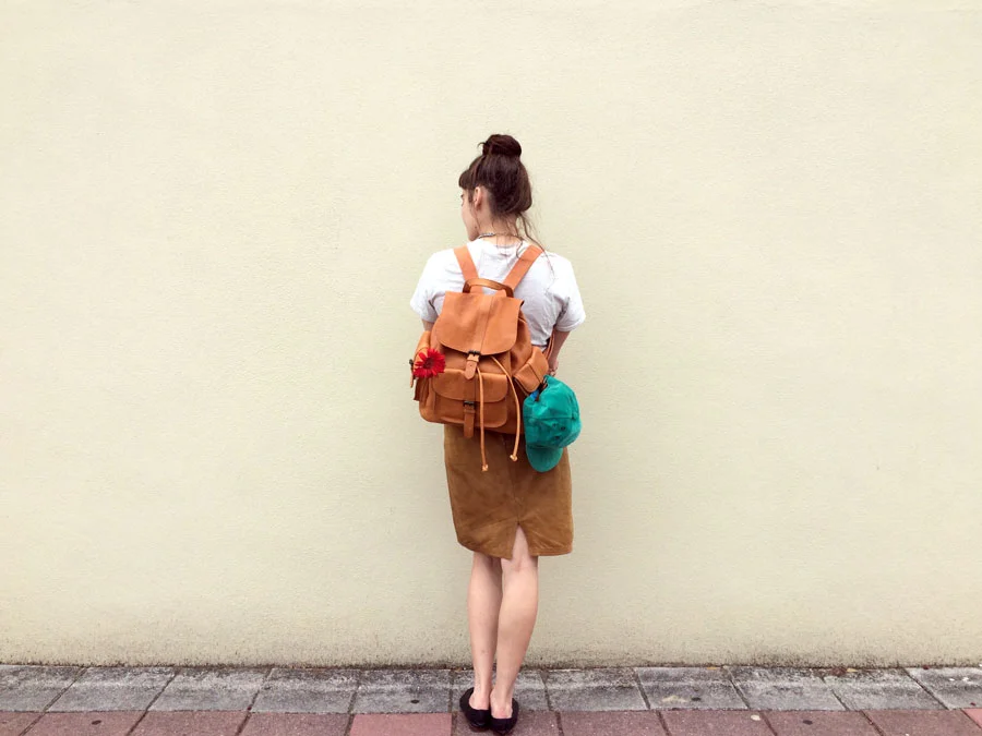Tiny Bursts of Color. The perfect caramel pebbled leather backpack with pockets galore to hold all of the essentials needed for an excursion into the wild or asphalt jungle. Backpack from UO with v intage snapback and fresh red daisy. All clothes are vintage and models own.