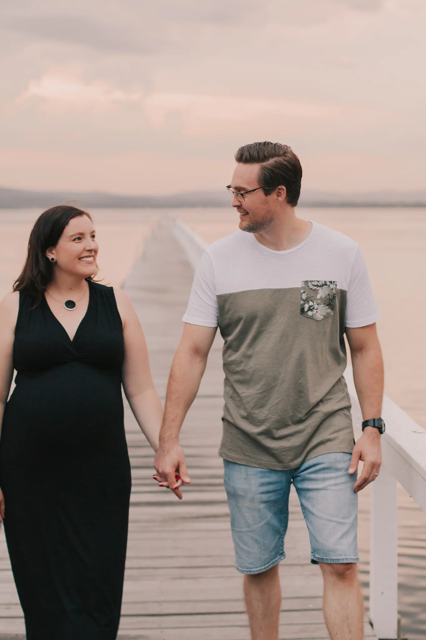 pregnant couple holding hands walking
