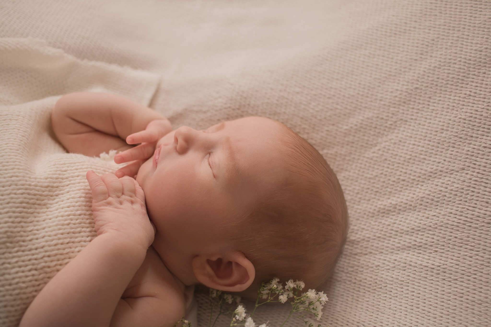 side profile of baby with hands under her chin