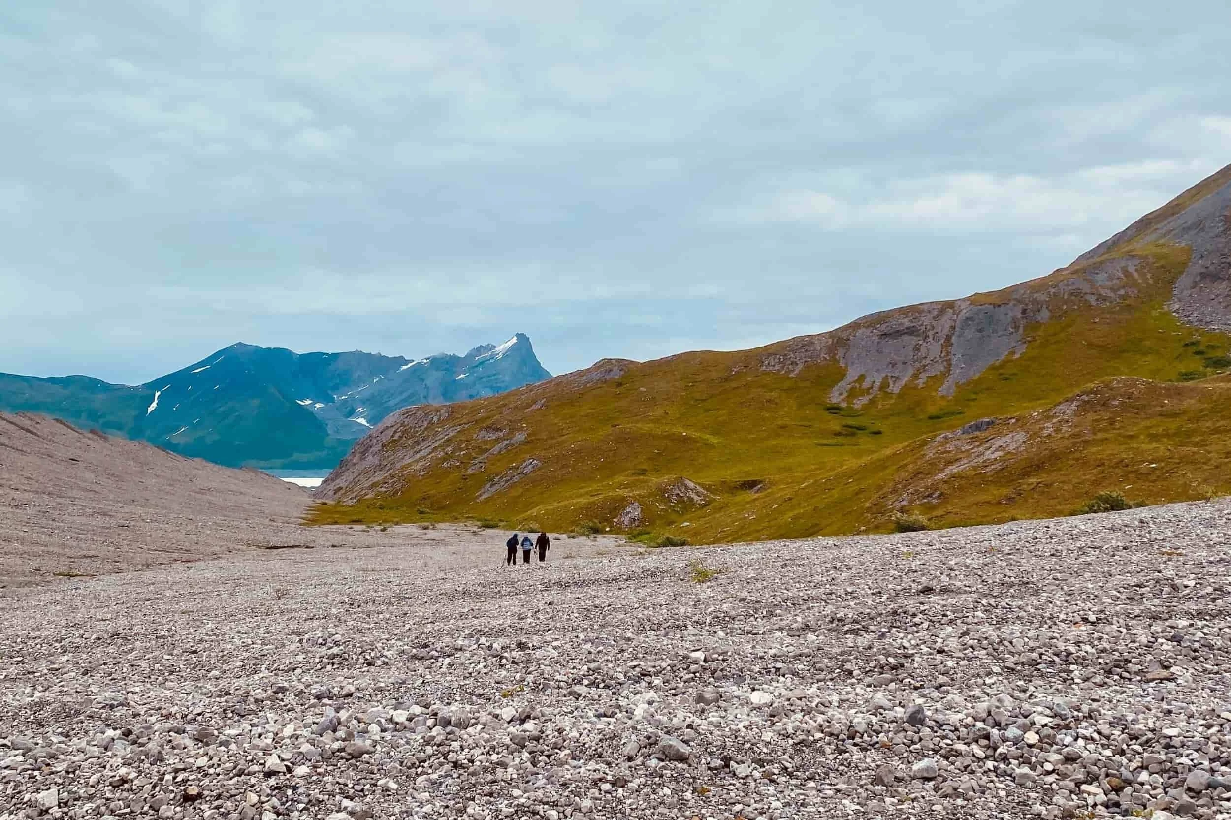 Two hikers walking a gravel bar in the Wrangell mountains.