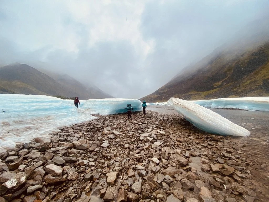 Backpackers walking through Aufeis in a river bed.