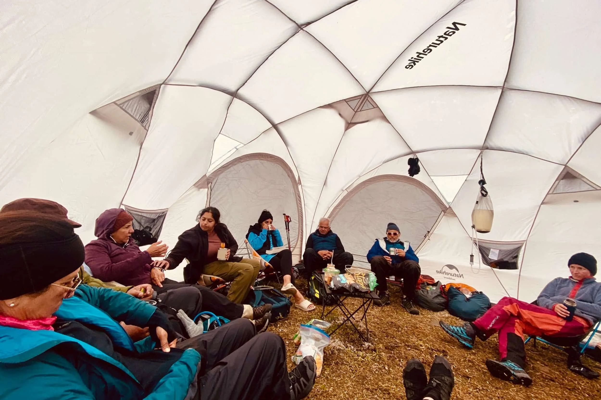 Campers drinking tea in a dome tent.