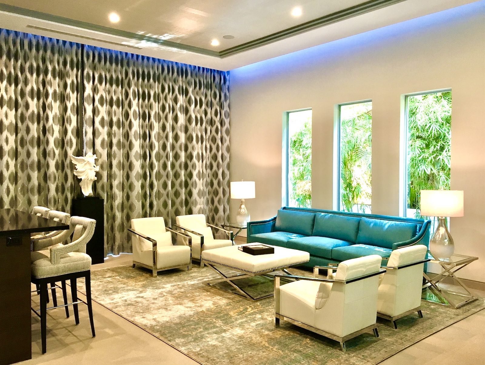 Modern living room interior design in Fort Lauderdale featuring contemporary seating, floor-to-ceiling drapery, layered lighting, and tropical views.