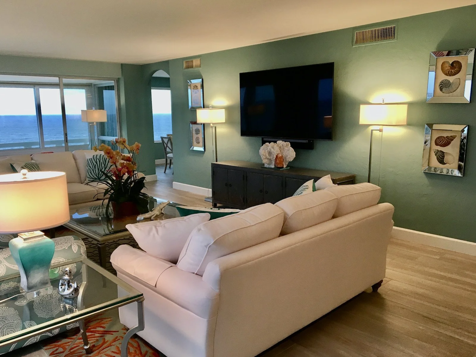 Ocean reef's modern coastal living room TV wall with dark blue credenza and two flanking floor lamps at Ocean Reef Club