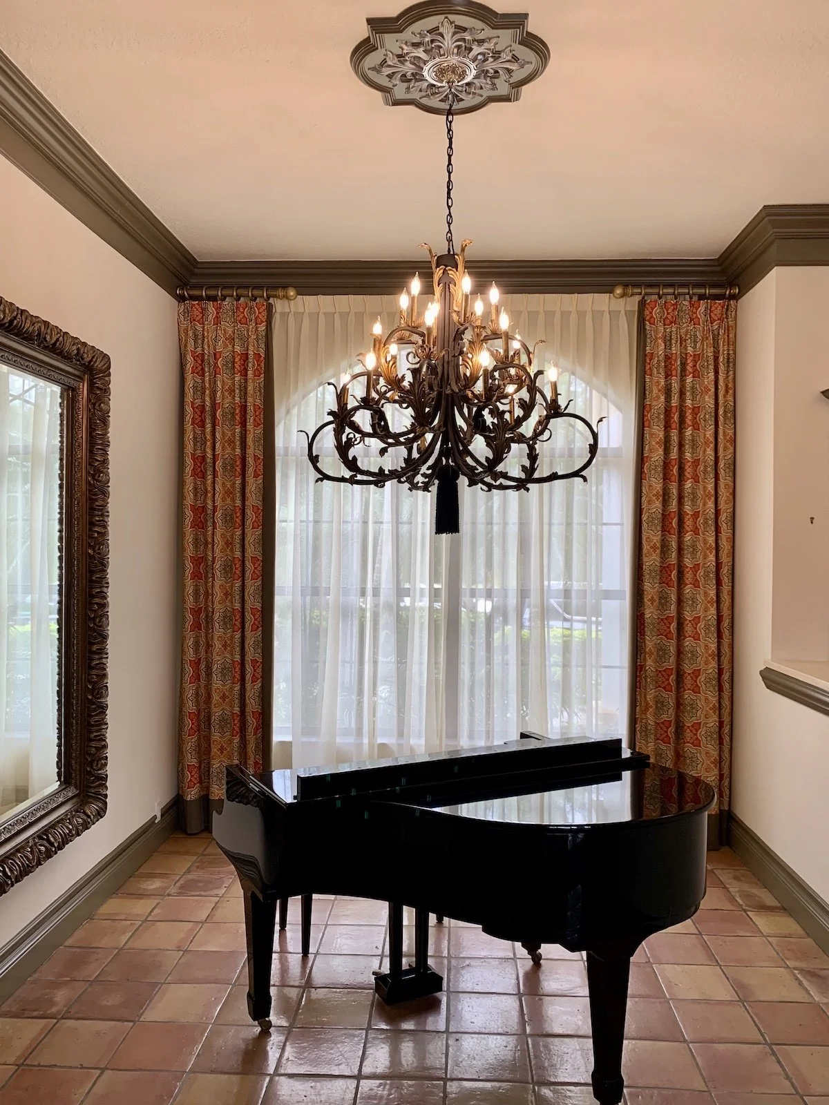 modern Mediterranean piano room with large chandelier and mirror