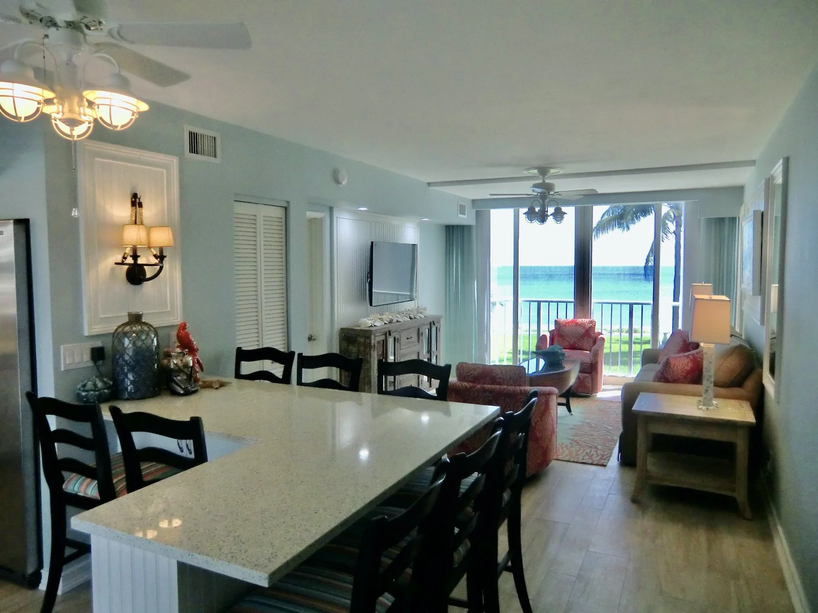 coastal living room with aqua walls, tan sofa and coral color chairs with an eat in bar at Ocean Reef Club
