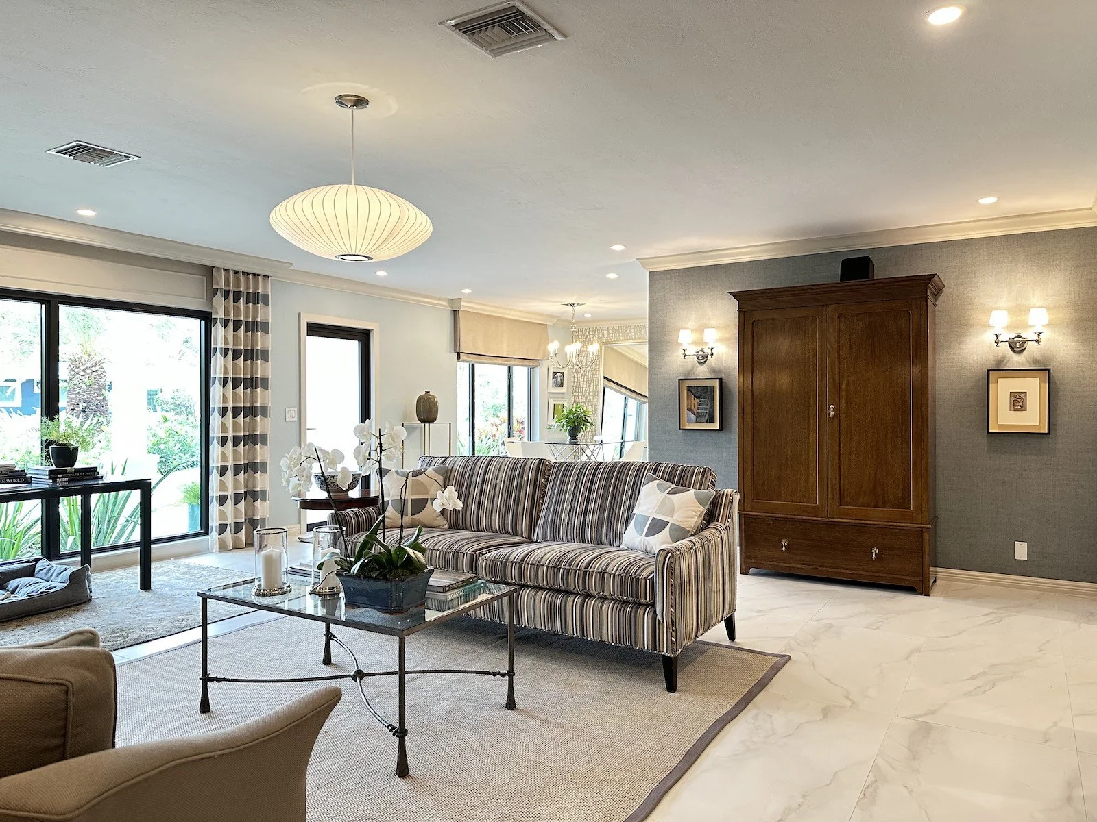living room with modern striped sofa and traditional armoire with flanking modern sconces in a Fort Lauderdale home