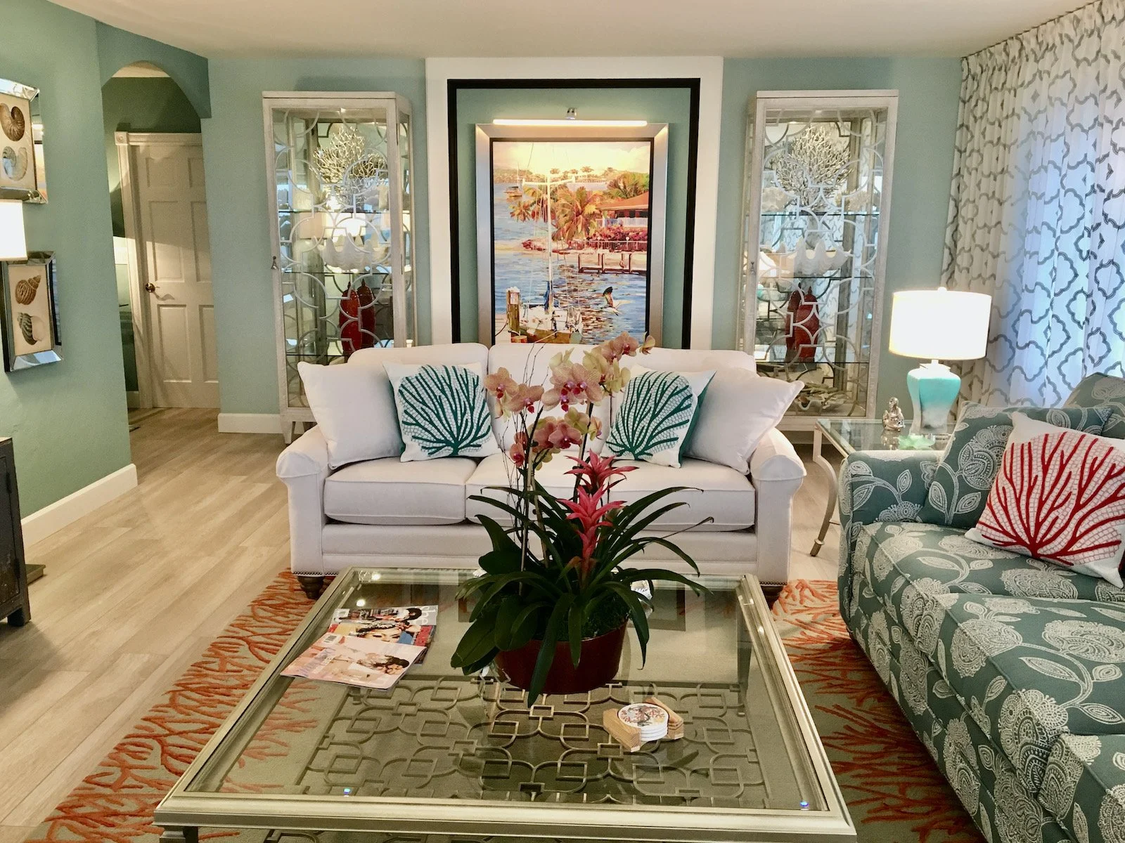modern coastal living room with white and sea foam green with tropical artwork and 2 armoires at Ocean Reef Club