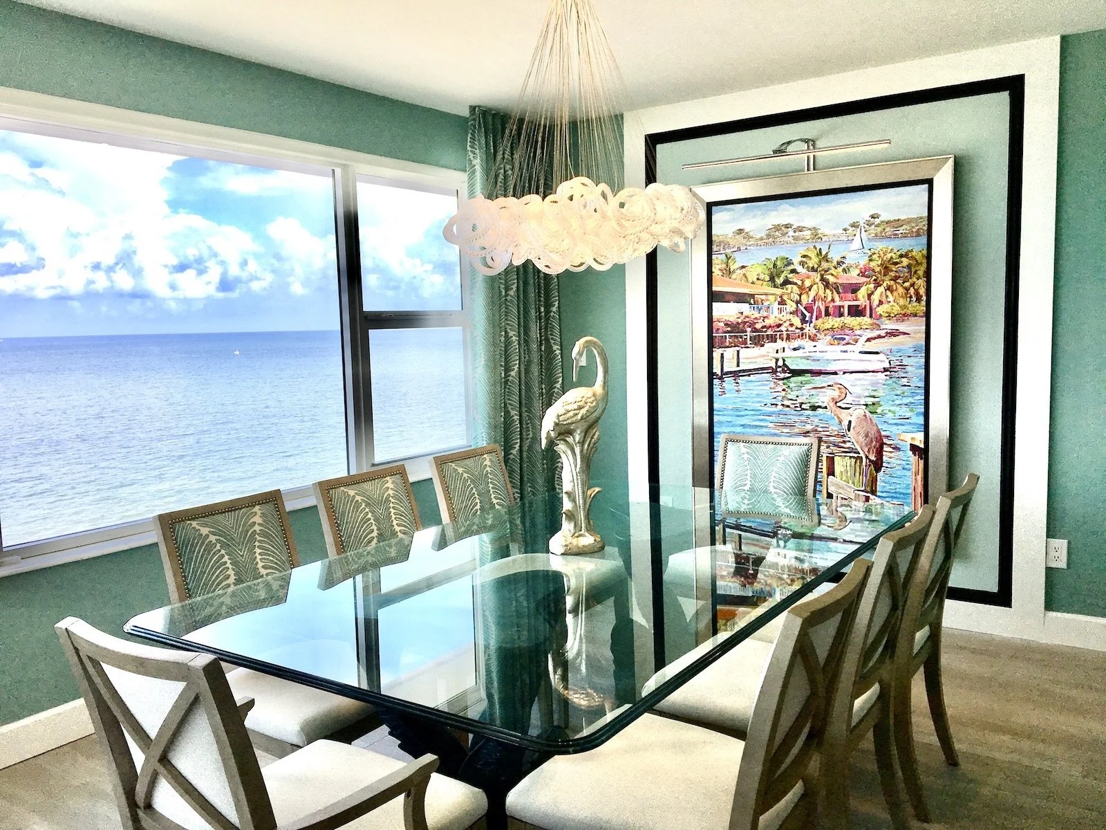 dining room with aqua green walls and large architectural tropical artwork, glass top table over looking the ocean at Ocean Reef Club