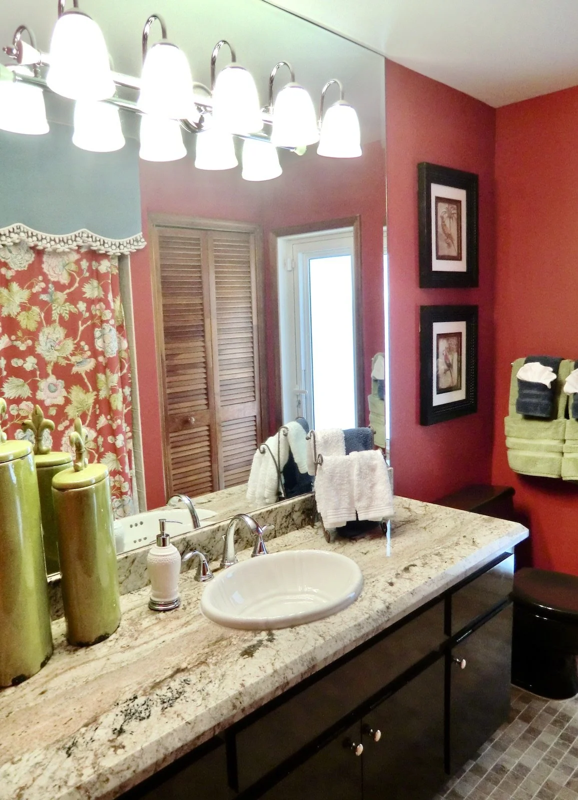 dramatic guest bathroom with red walls, coco brown cabinetry, and green accents in Delray Beach