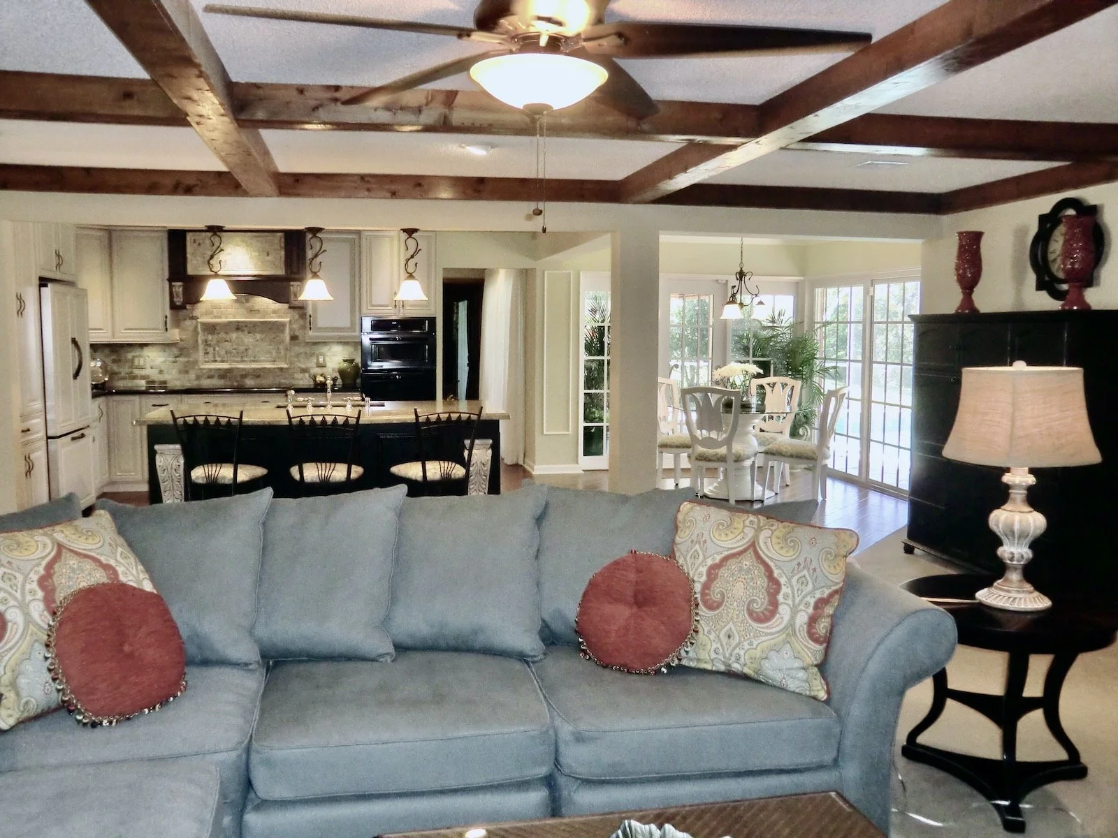 transitional family room with blue sofa looking into the traditional cream and black kitchen in Delray Beach