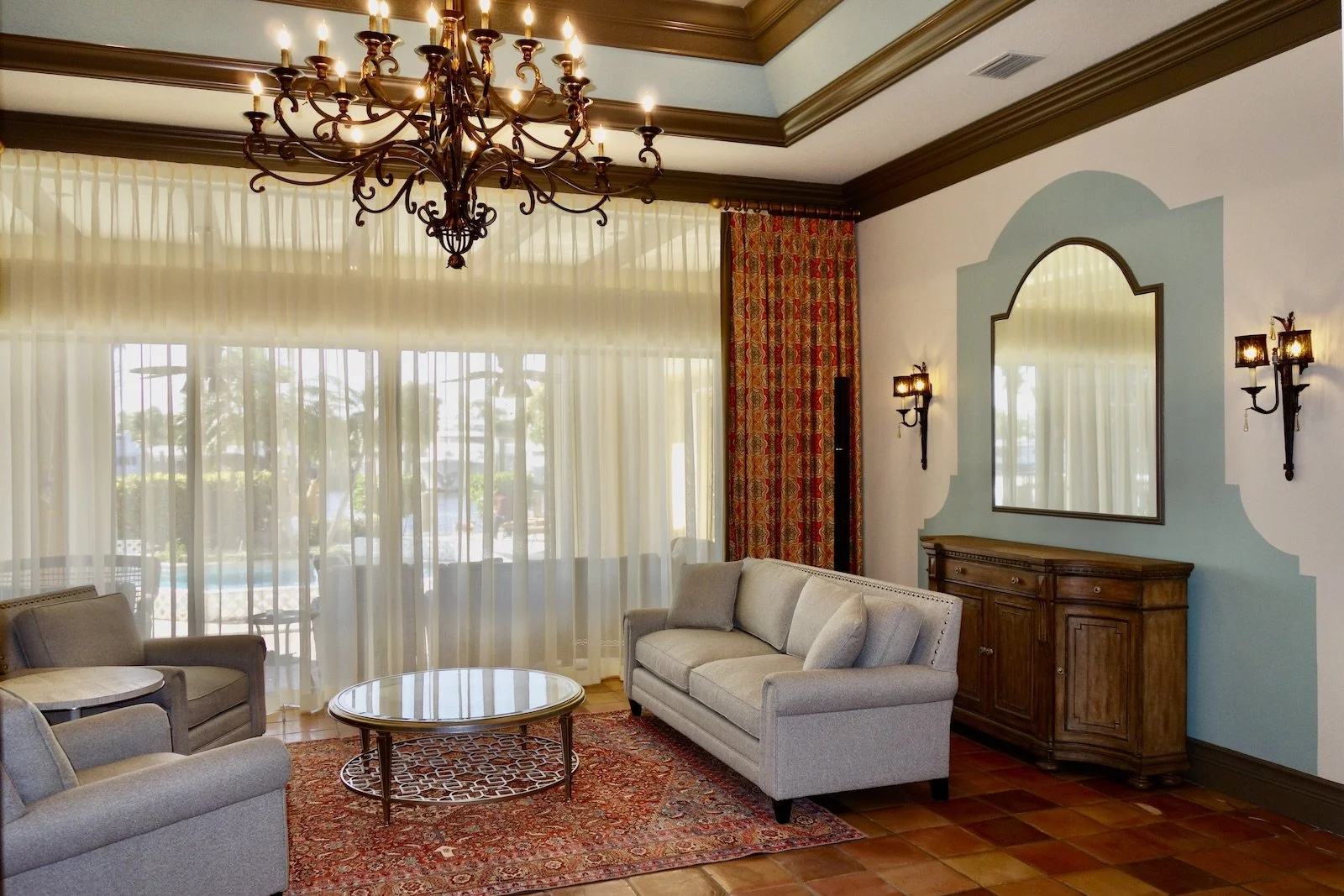 mediterranean living room with tan sofa and two chairs with wrought iron chandelier in Boca Raton