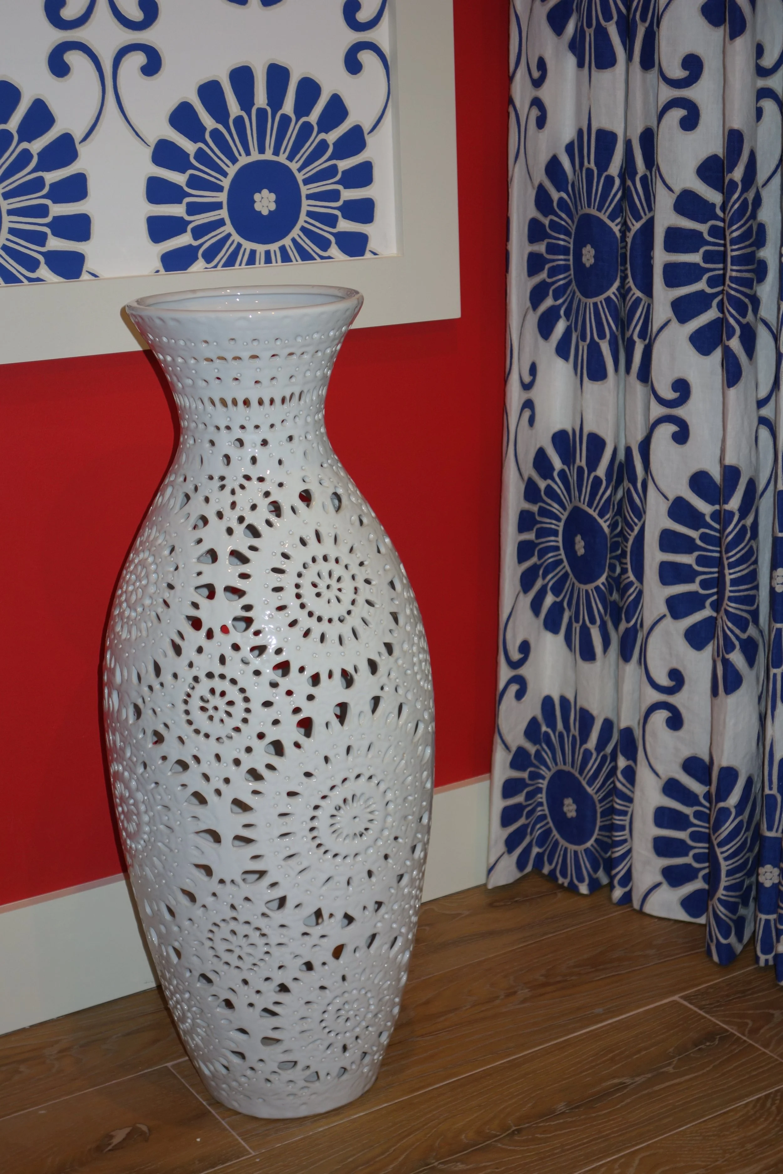transitional red bedroom with a white vase and Batik drapes