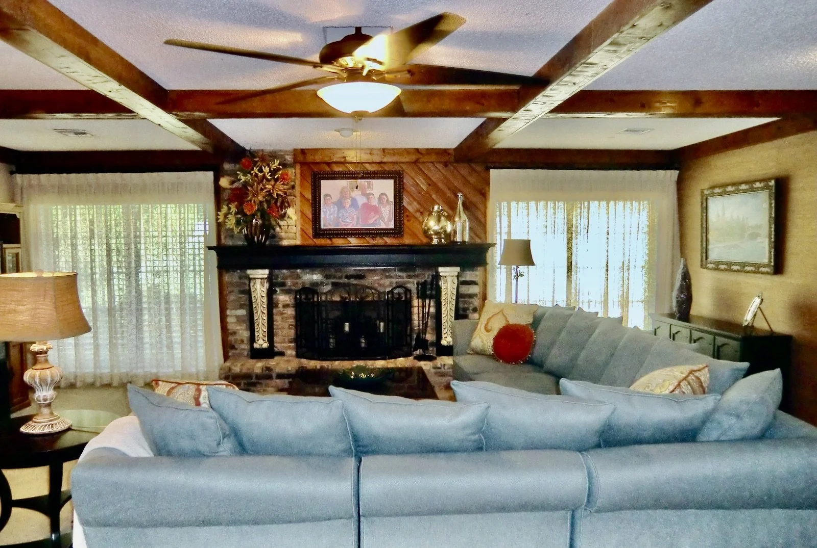 Coastal family room with blue sofa facing the brick and black mantel with cream corbels in Palm Beach