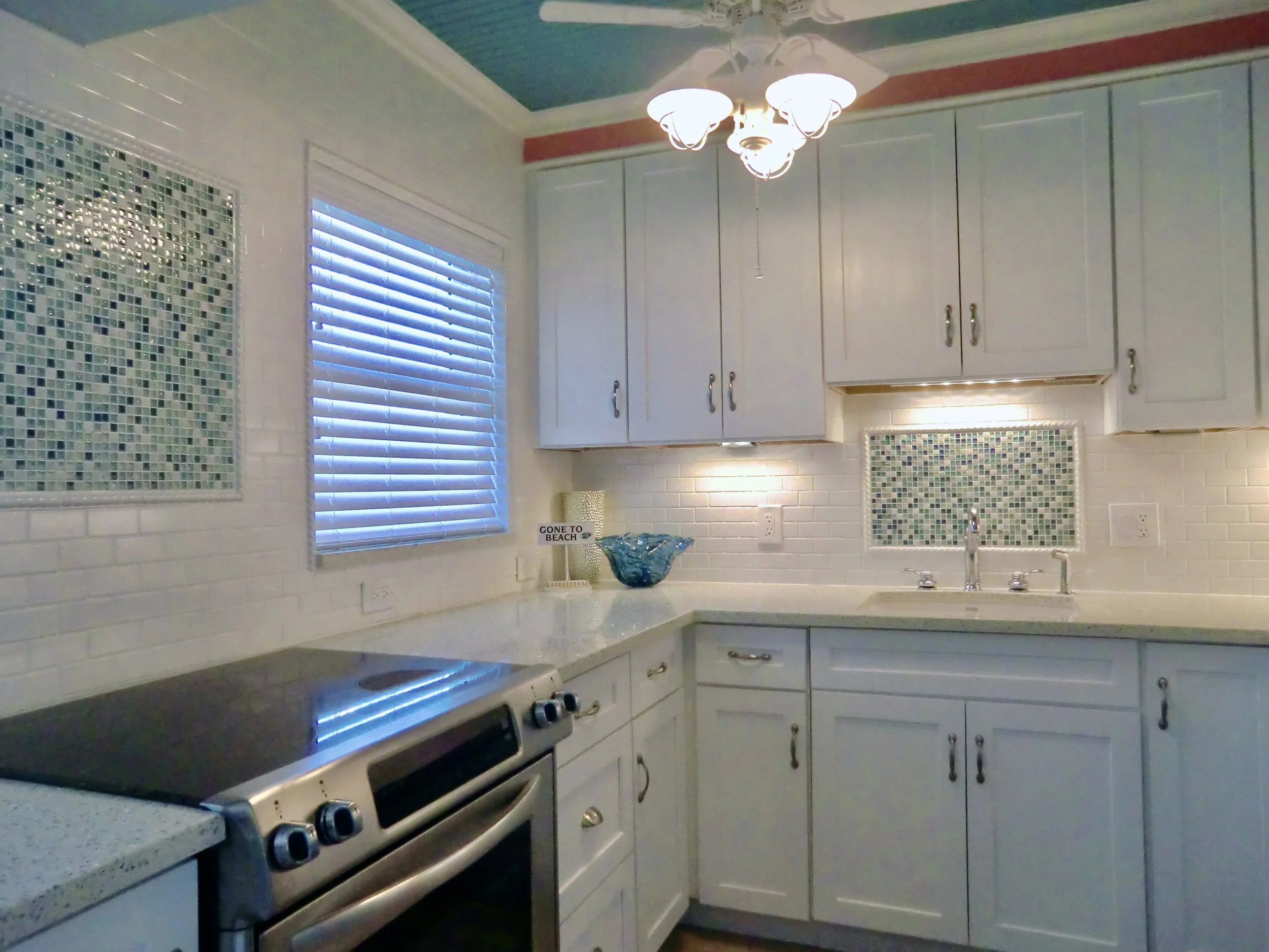coastal style kitchen with white custom cabinets and blue beadboard ceiling