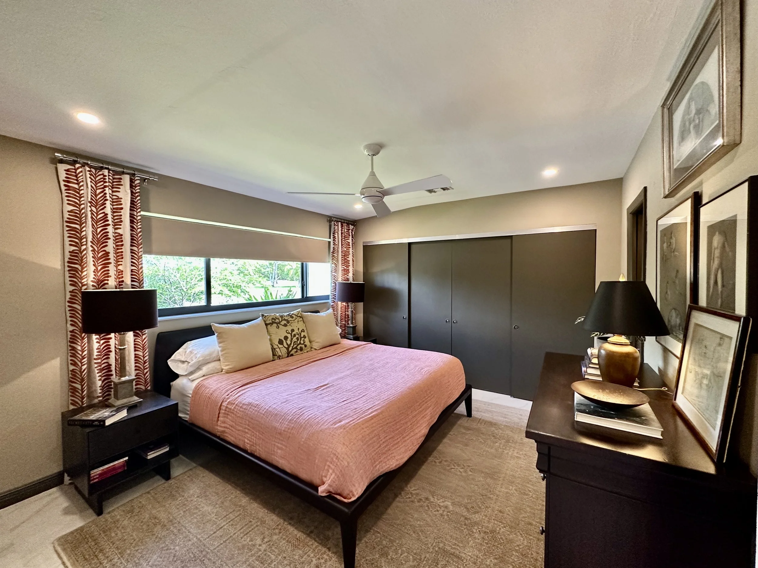 Modern bedroom with tan walls and dark brown doors with rust color drapes and bedding in Fort Lauderdale