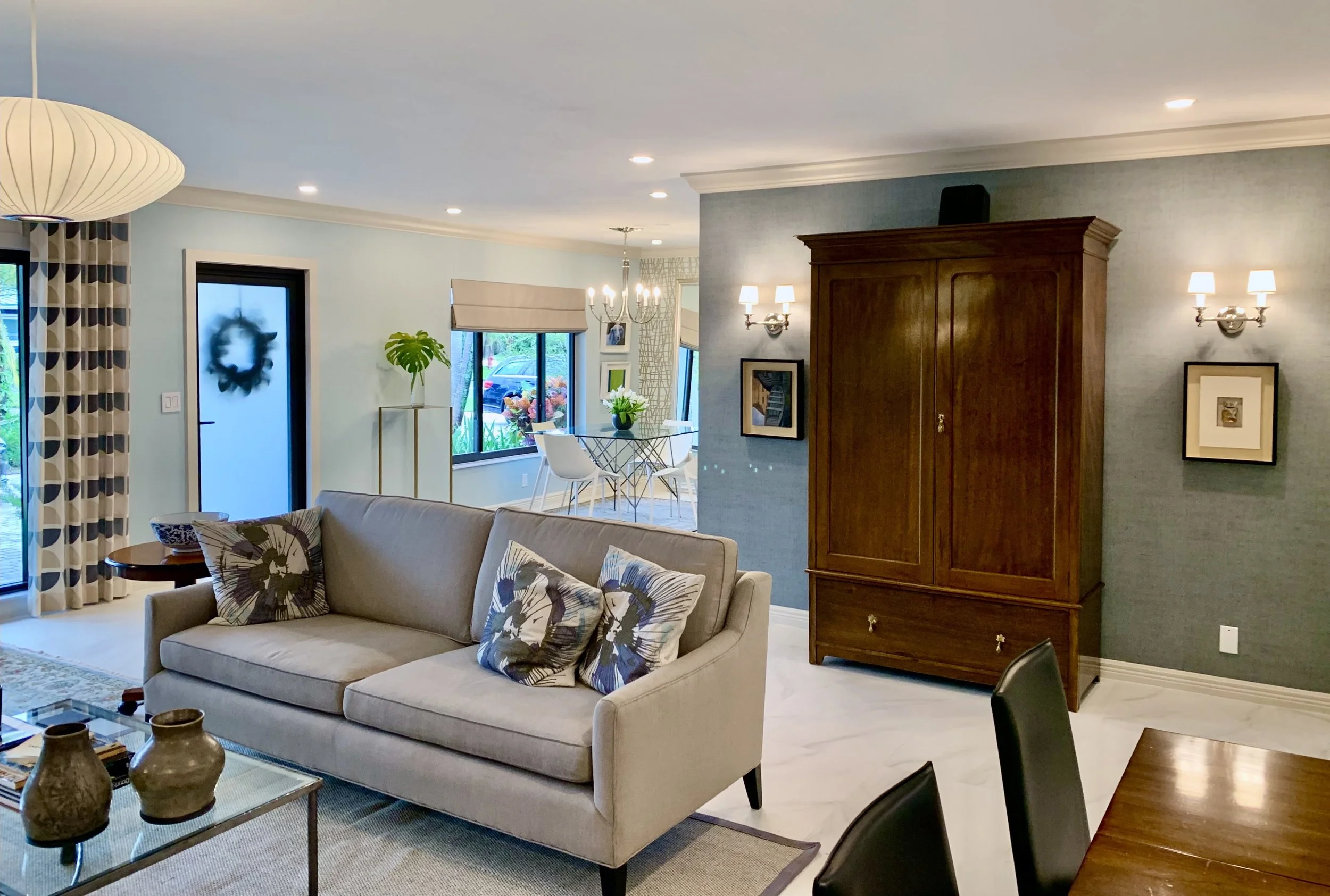 Modern living room with traditional armoire with flanking sconces and moldings in Fort Lauderdale