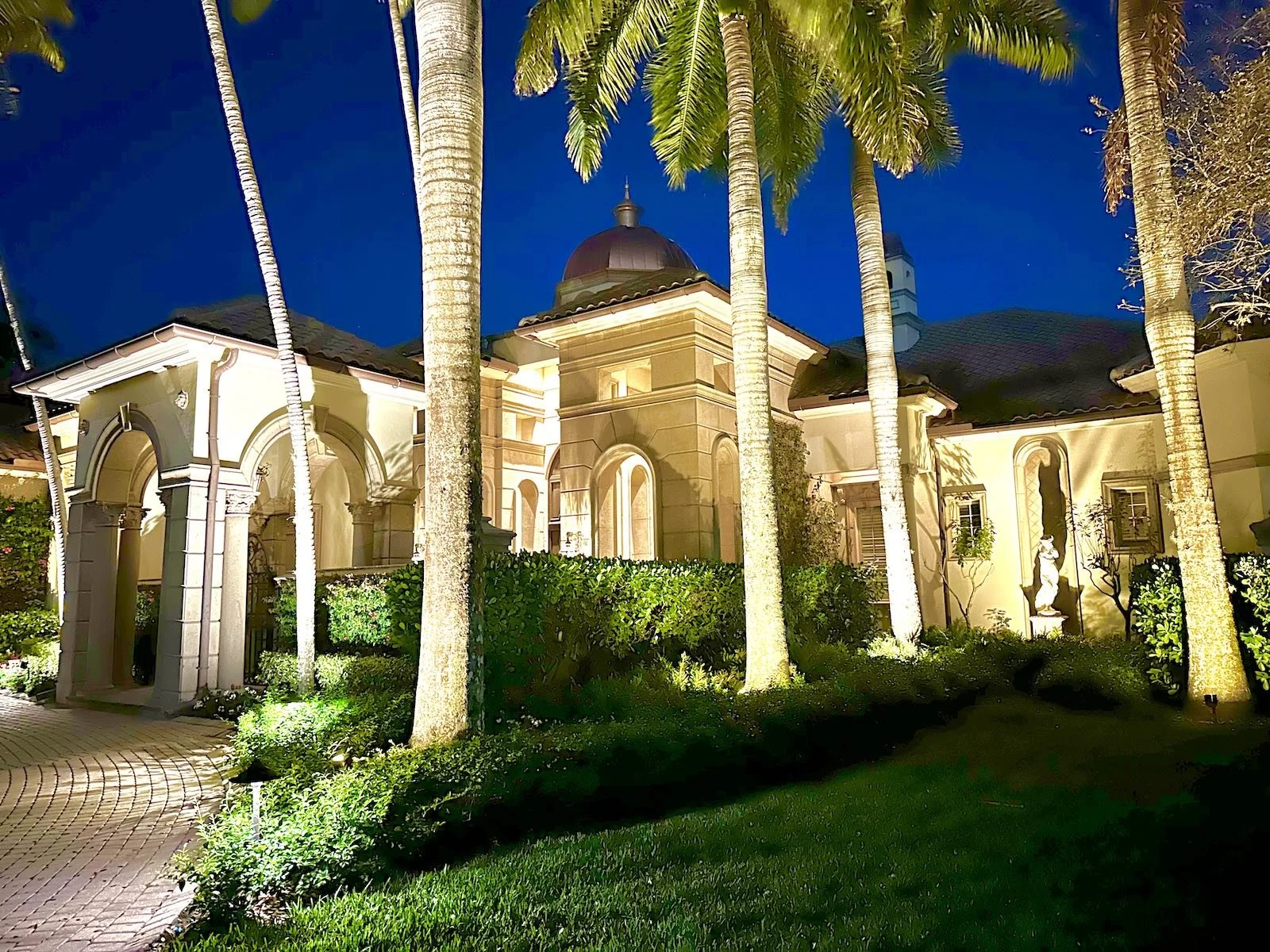 front of home with Mediterranean architecture and landscape lighting at night