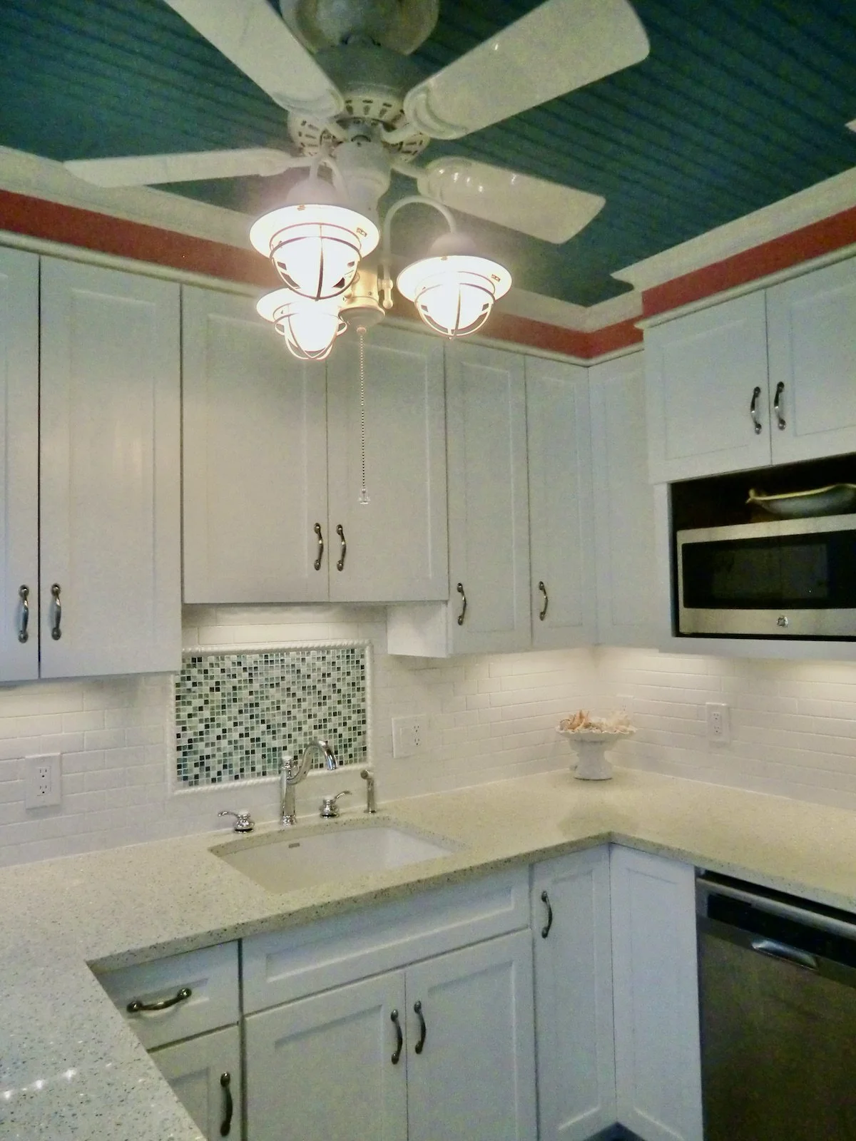 coastal style kitchen with white custom cabinets and blue beadboard ceiling at Ocean Reef Club