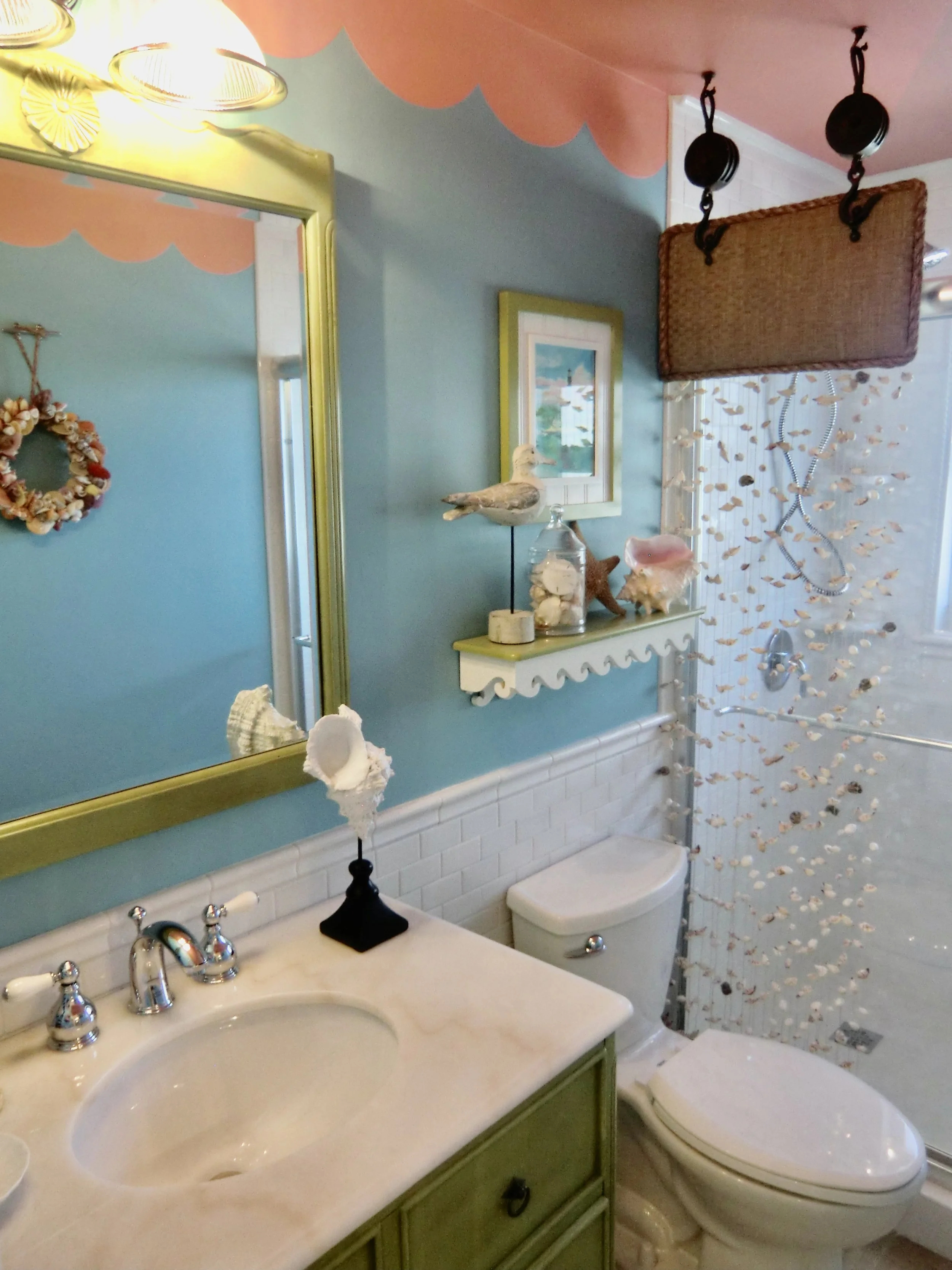colorful tropical bathroom with aqua walls, coral ceiling and green cabinetry