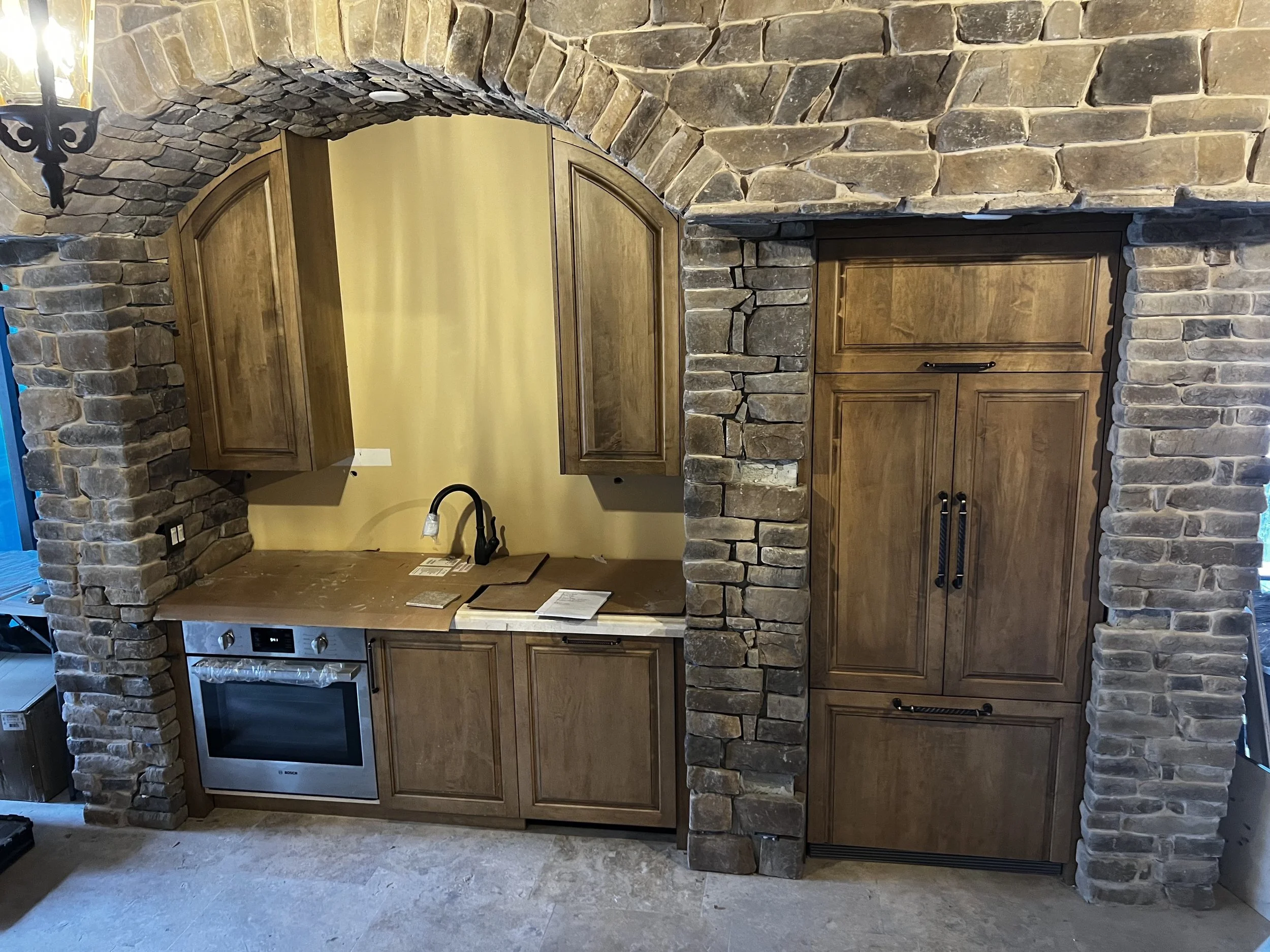 mediterranean kitchen with rustic cabinets and stone arch in Boca Raton