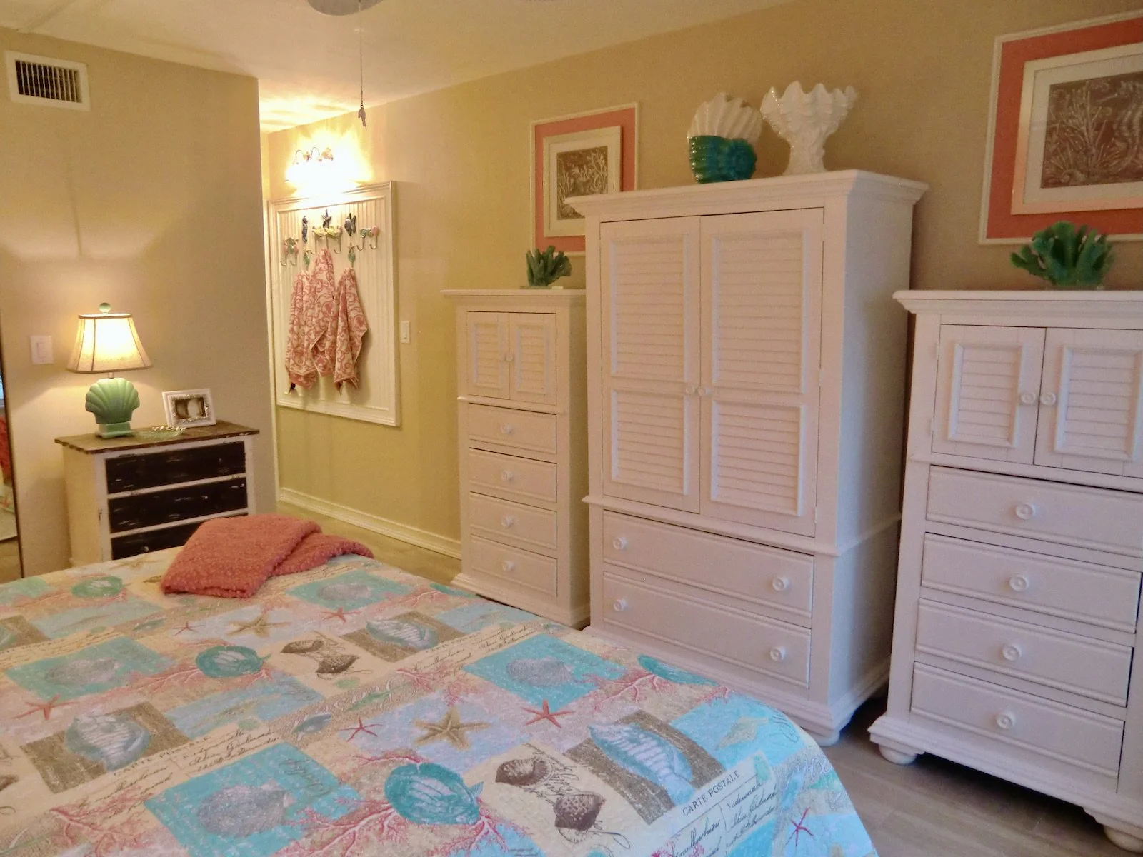 coastal bedroom with coral color accent wall and white furniture