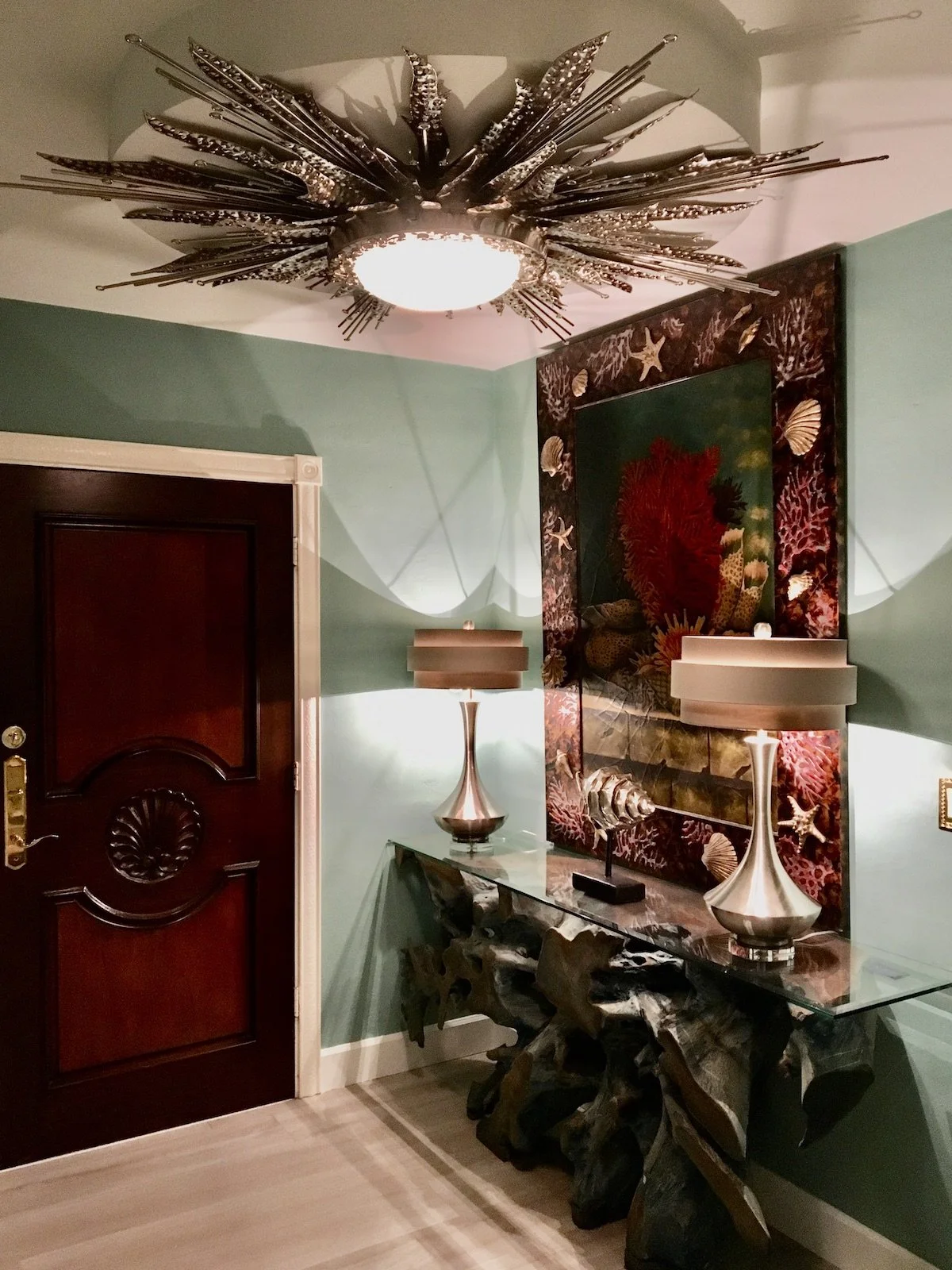 Luxury coastal foyer with driftwood table and large tropical artwork