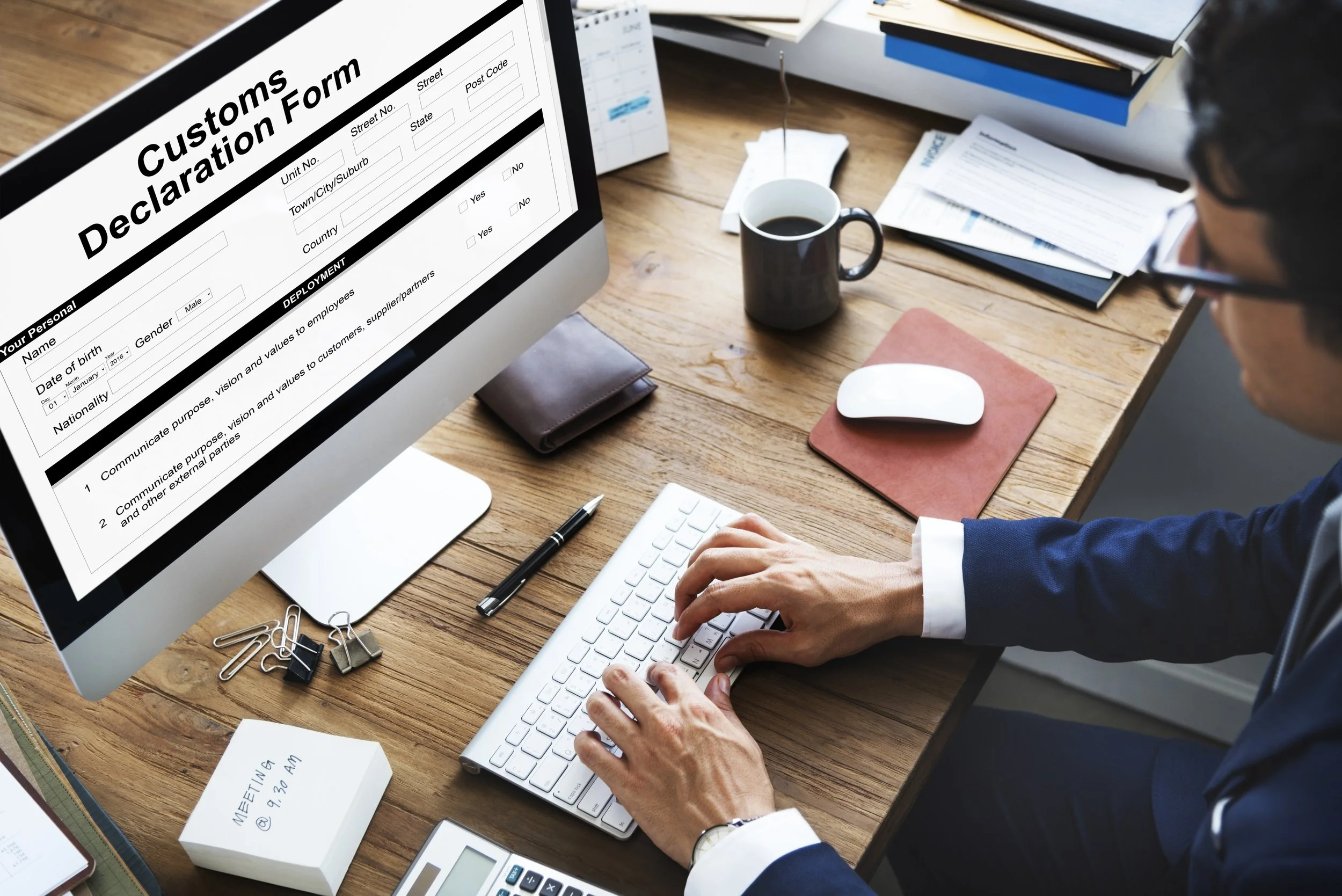 Photo of a man sitting at a desk and filling out a customs declaration form