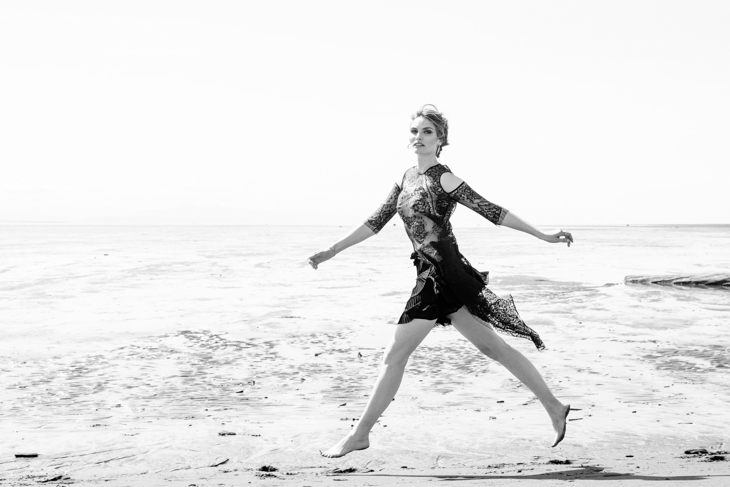 Black and white photo of model running on the beach. 
