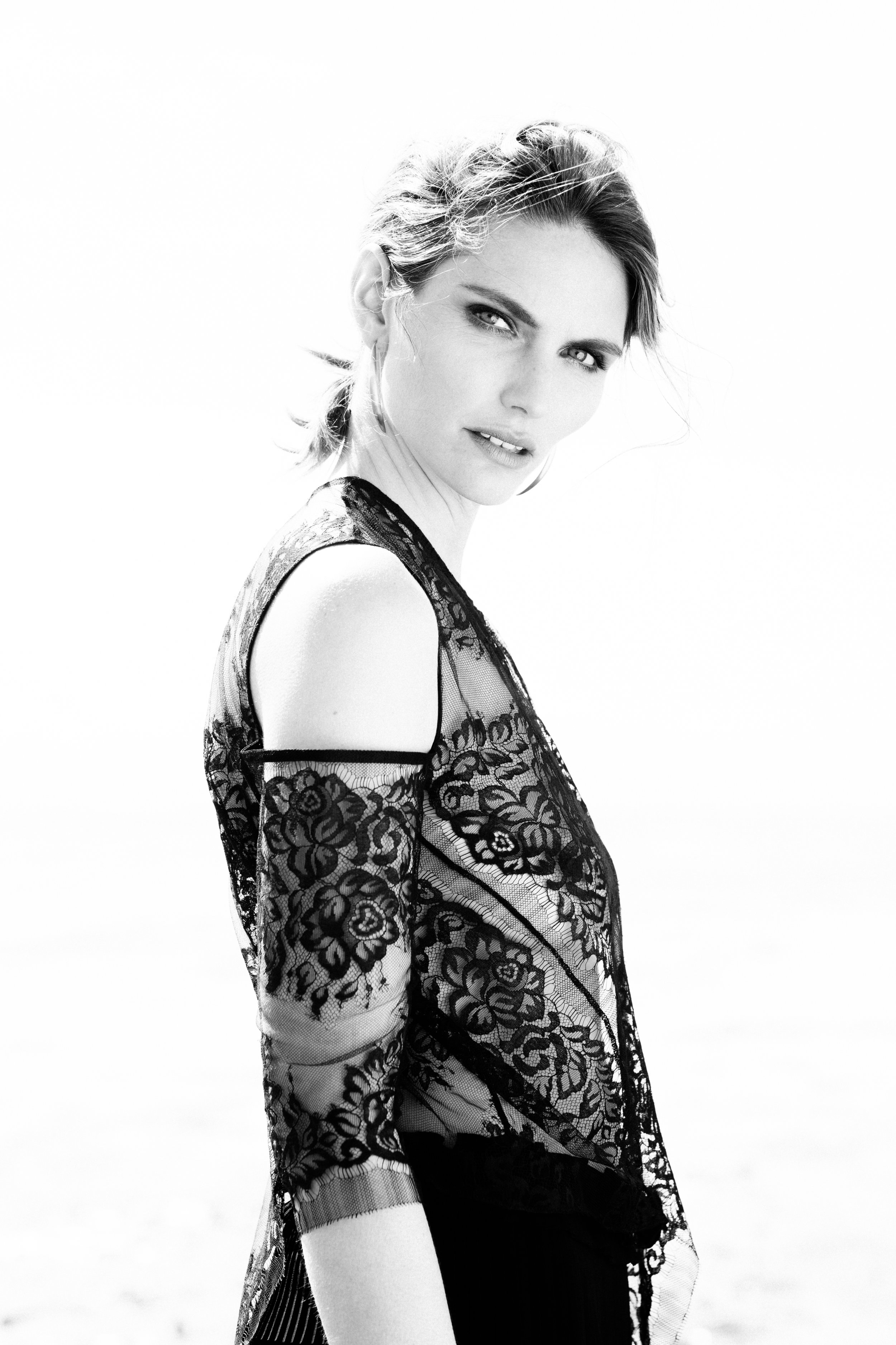 Black and white editorial fashion photo of model wearing black lace dress. 