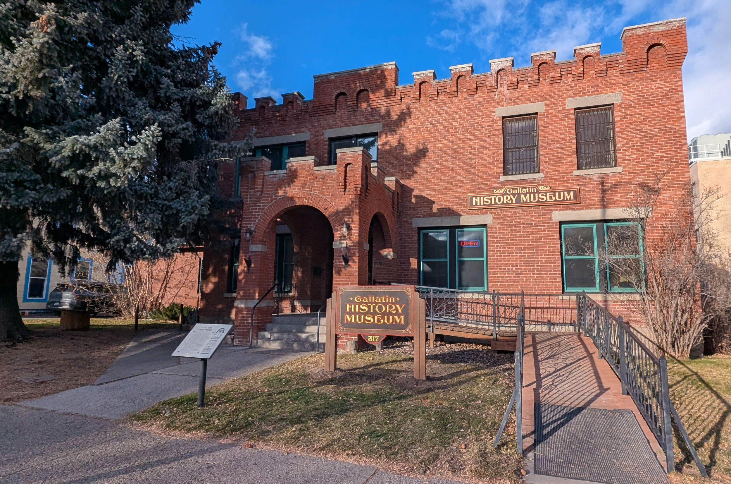 The front of the Gallatin History Museum building, with two signs and a historical plaque detailing the building's history as a jail.