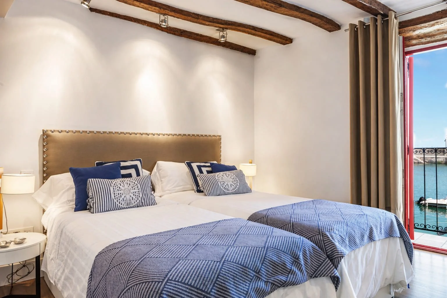 Dormitorio con vistas al mar en Mundaka con vigas de madera y decoración de estilo rústico costero