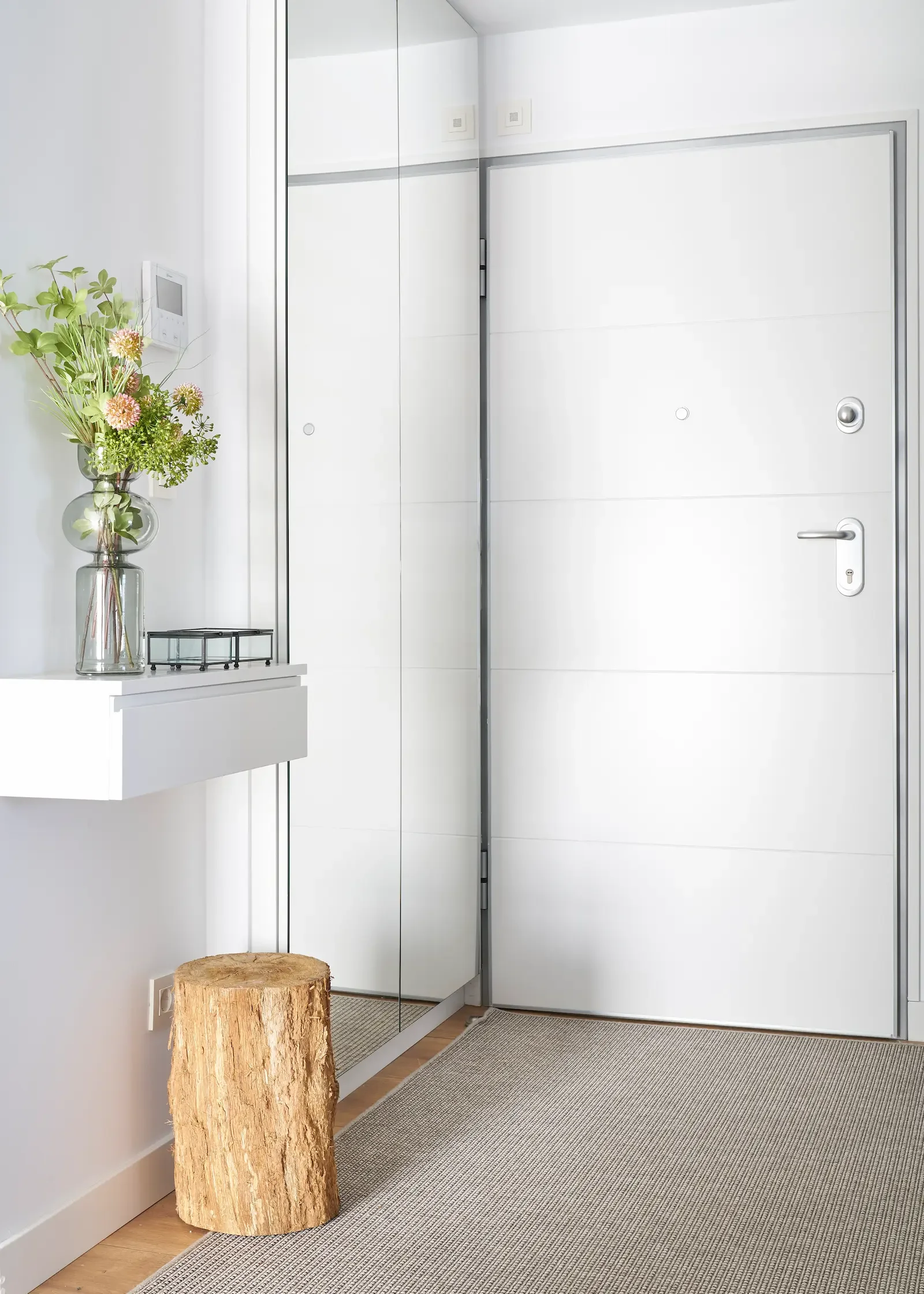 Recibidor moderno con espejo de pared, mueble flotante y detalles en madera natural en proyecto de decoración y estilismo en Urduliz
