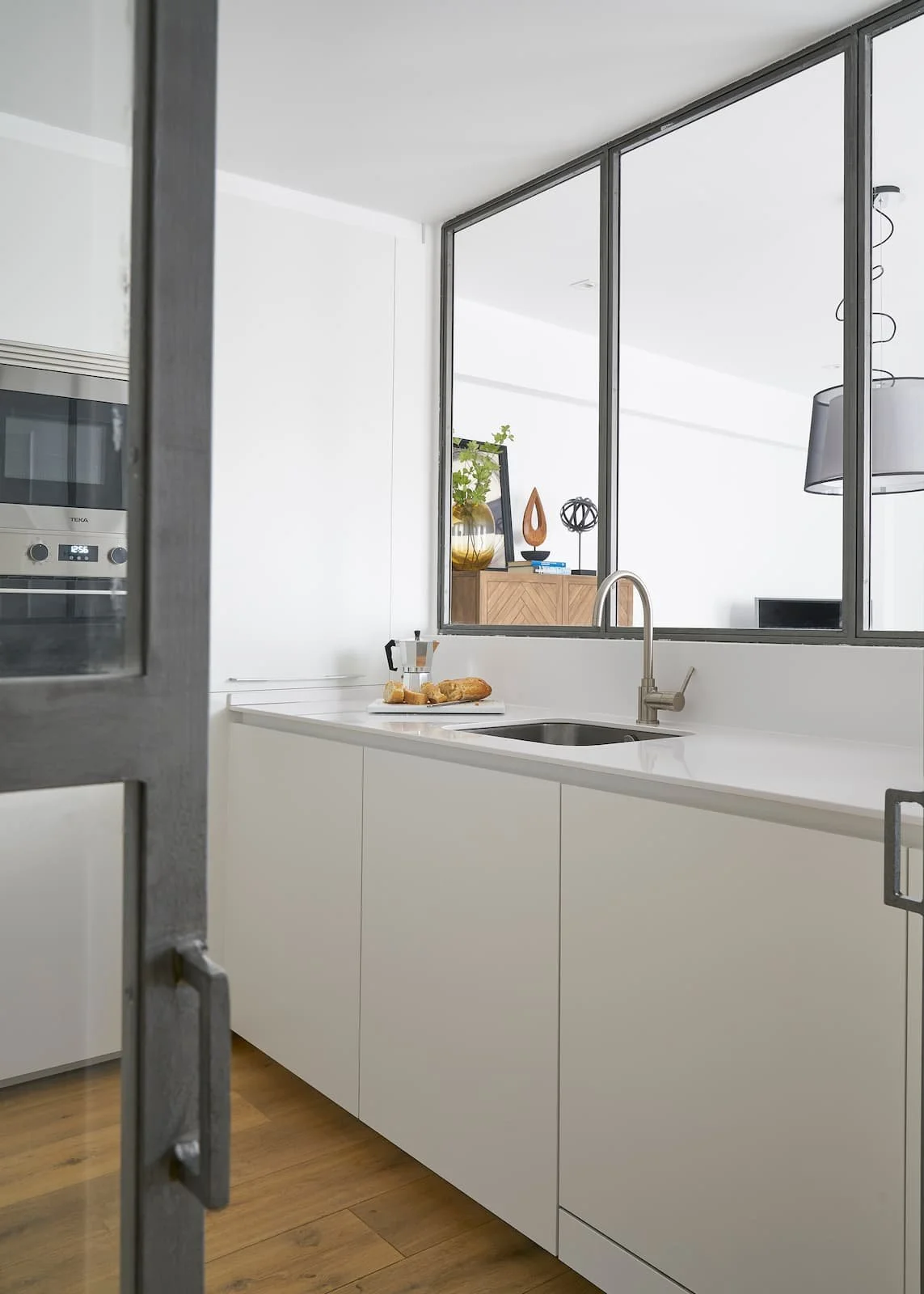 cocina blanca moderna con encimera continua y cerramiento de cristal en reforma integral en portugalete