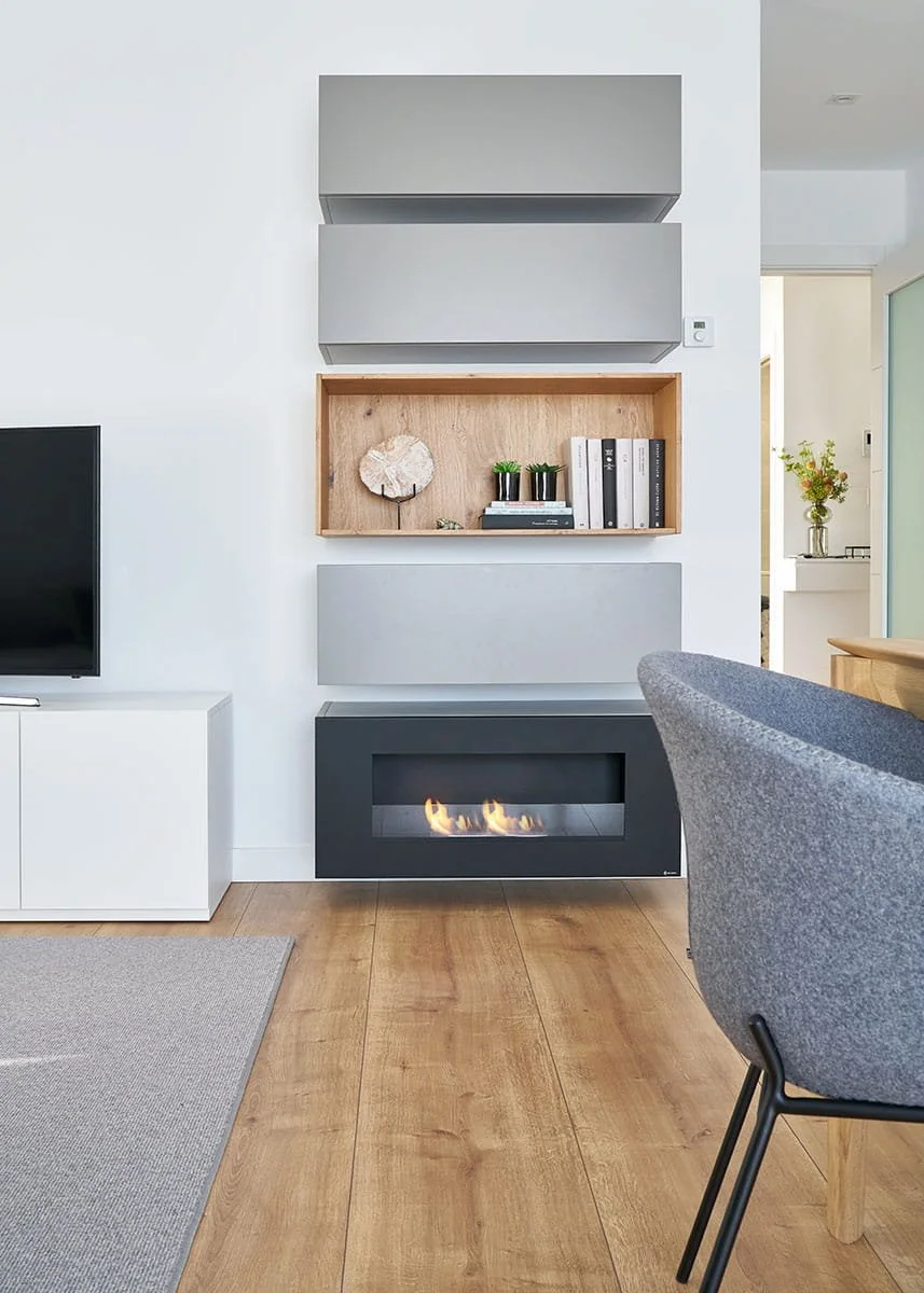 Salón moderno con chimenea y mueble de televisión en vivienda de Urduliz Bizkaia con estantería integrada. Proyecto de interiorismo.