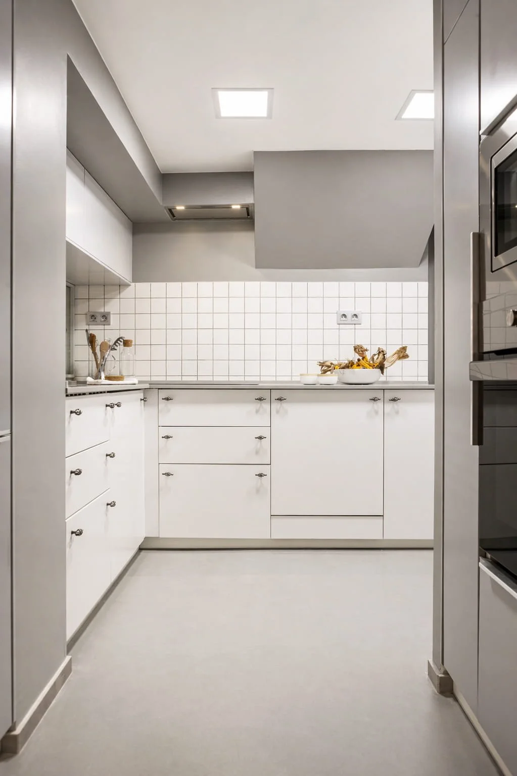 Cocina blanca con azulejo tipo metro y mobiliario a medida en vivienda reformada en Mundaka