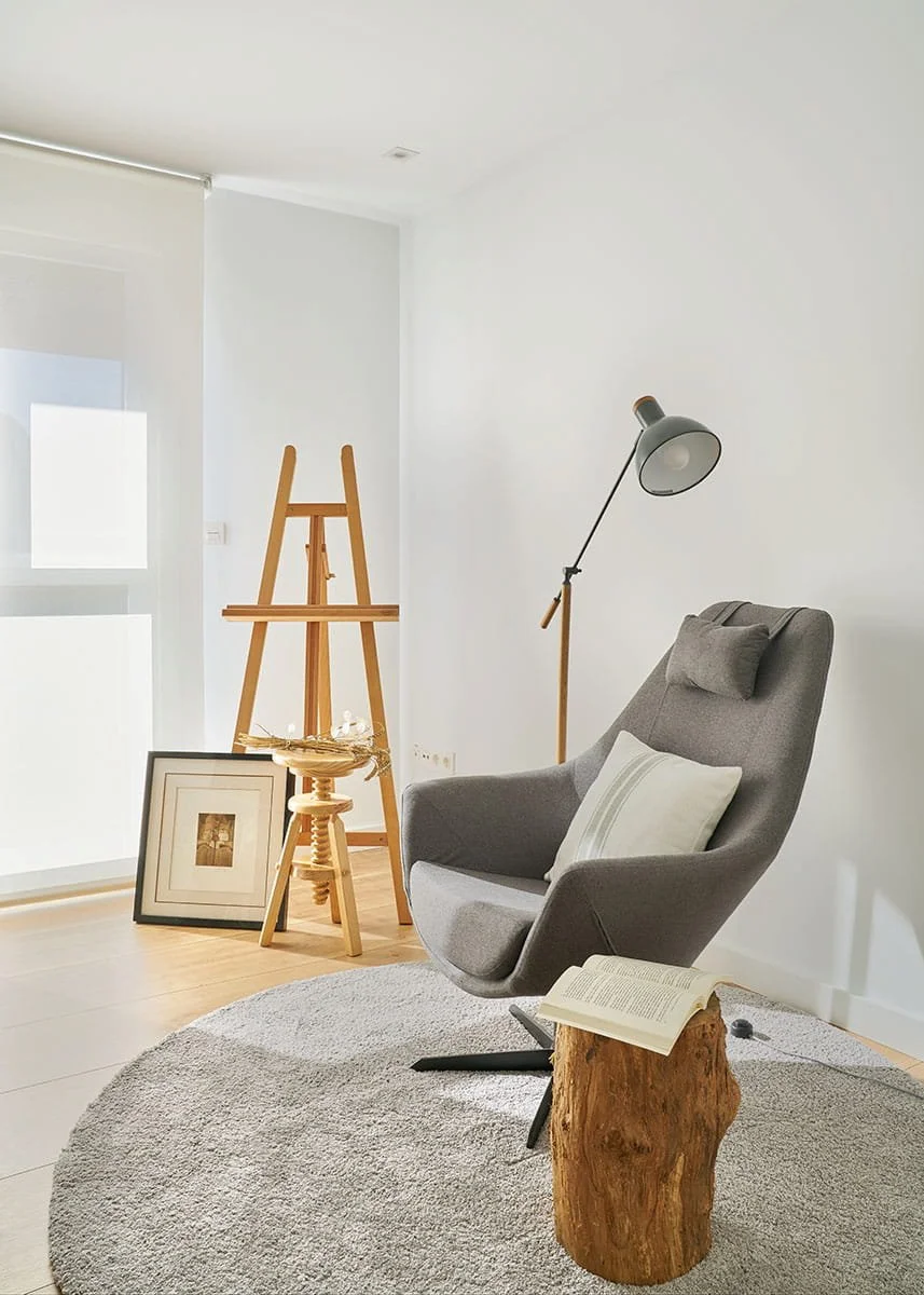 Rincón de lectura con sillón moderno tapizado en tela gris y lámpara de pie en vivienda de Urduliz Bizkaia con decoración natural proyecto de interiorismo y estilismo.