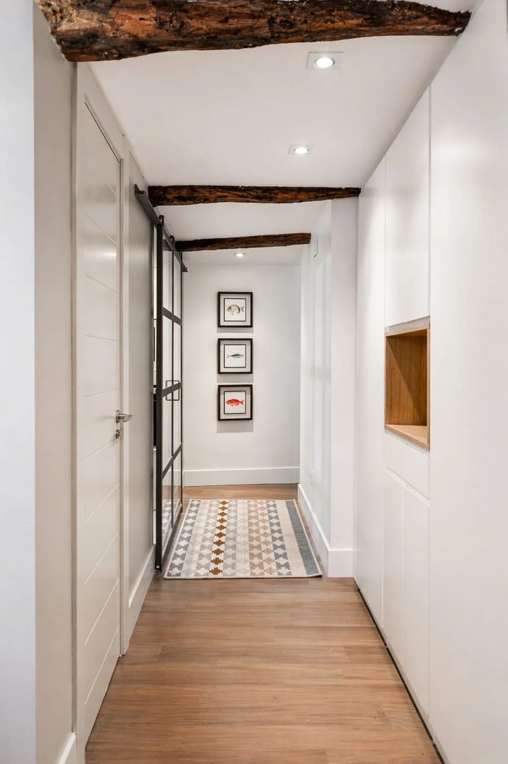 Pasillo reformado con armarios a medida y vigas de madera en vivienda de estilo rústico costero