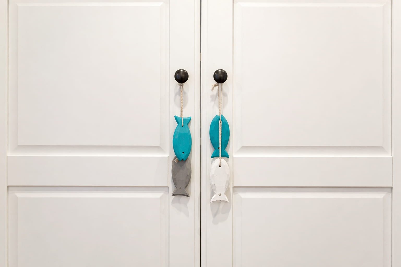 Detalle de armario con tiradores decorativos en forma de pez en dormitorio de estilo costero