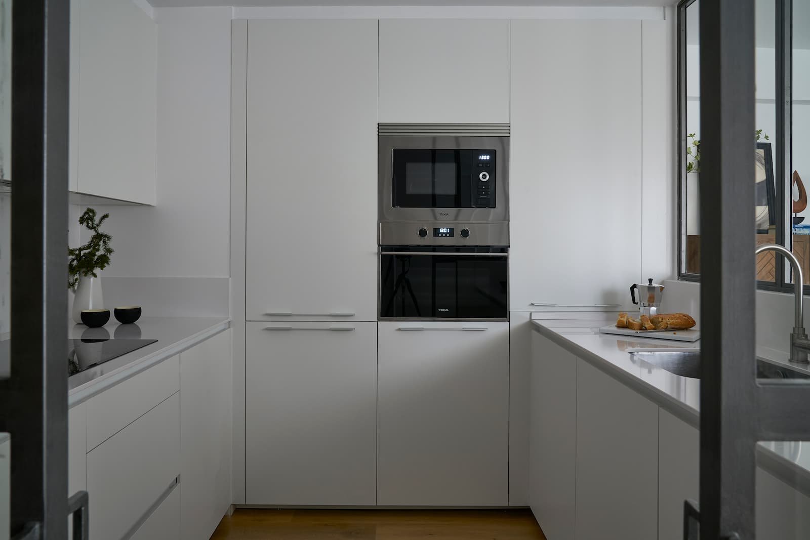 Cocina moderna blanca en reforma integral en Portugalete con mobiliario integrado y electrodomésticos empotrados
