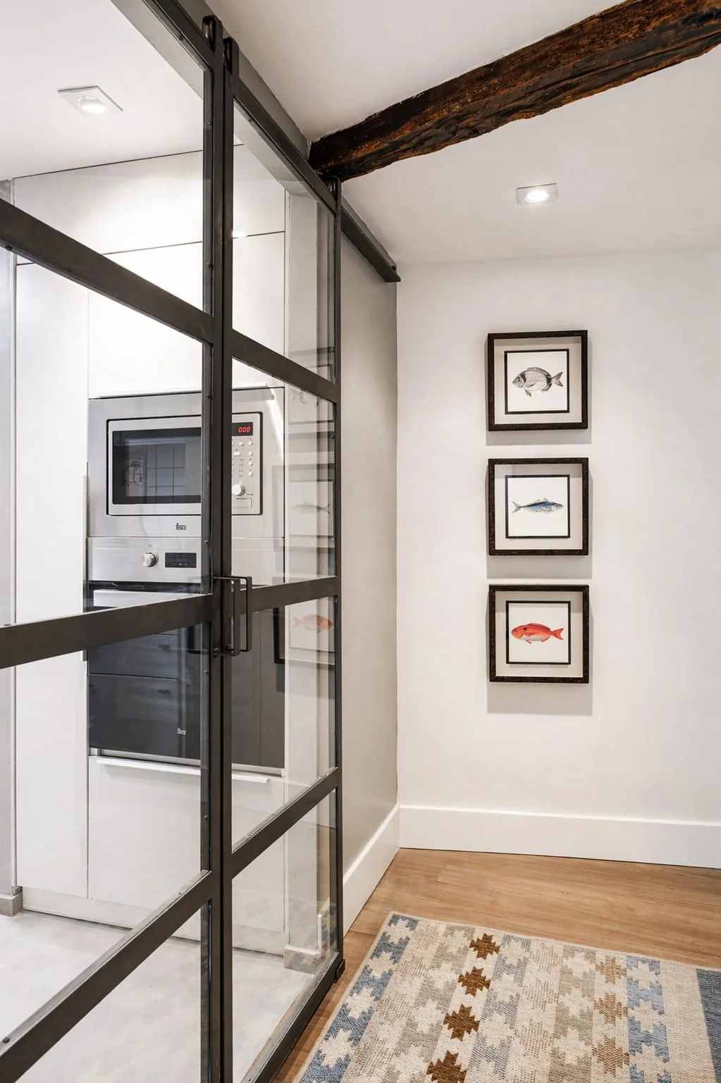 Acceso a cocina con cerramiento de hierro y vidrio en vivienda reformada de estilo rústico costero