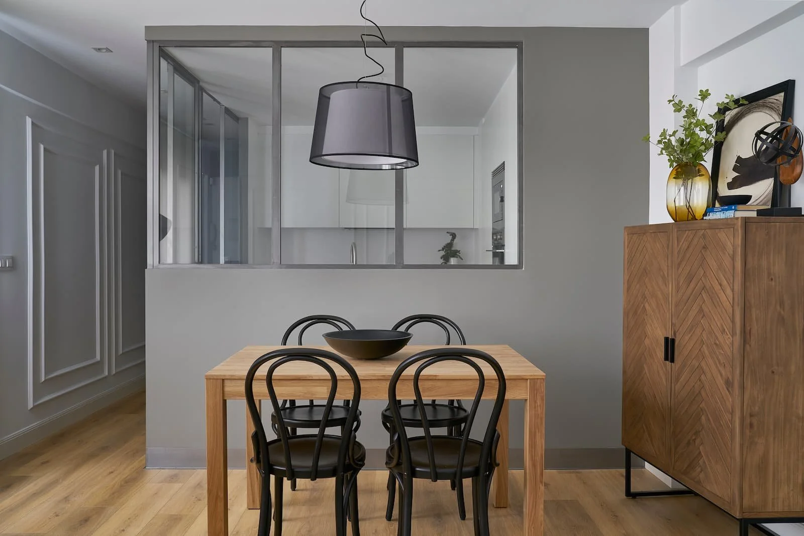 comedor con mesa de madera y cocina abierta con cerramiento de cristal en reforma integral en portugalete