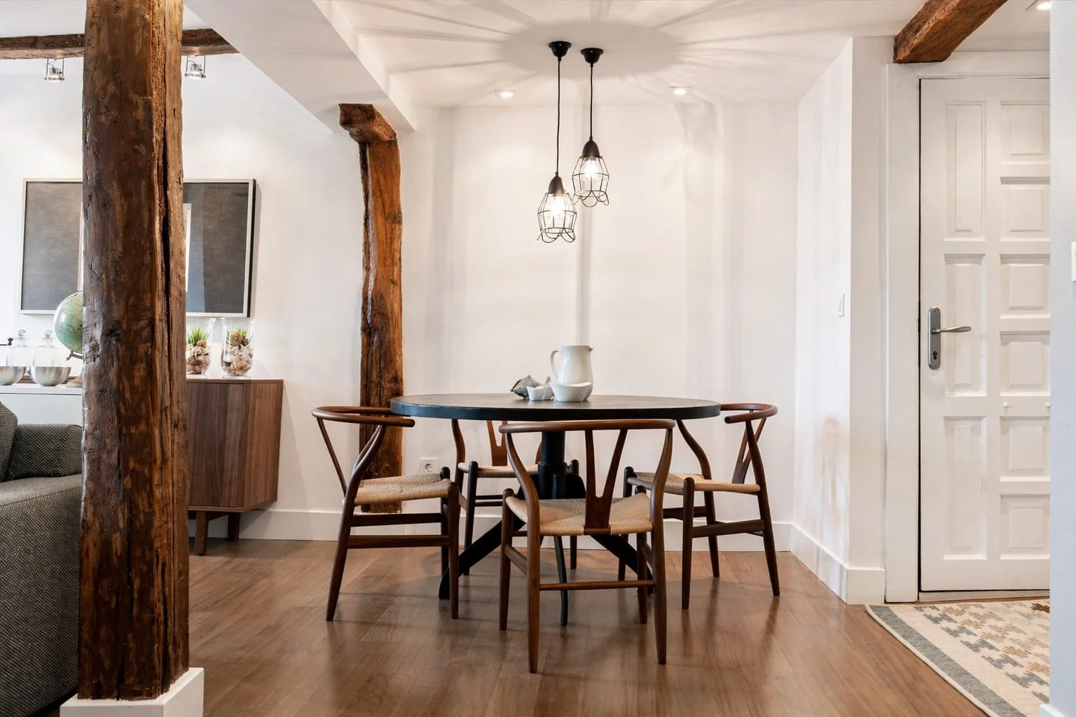 Comedor con mesa redonda y sillas de madera en vivienda reformada en Mundaka con estilo costero