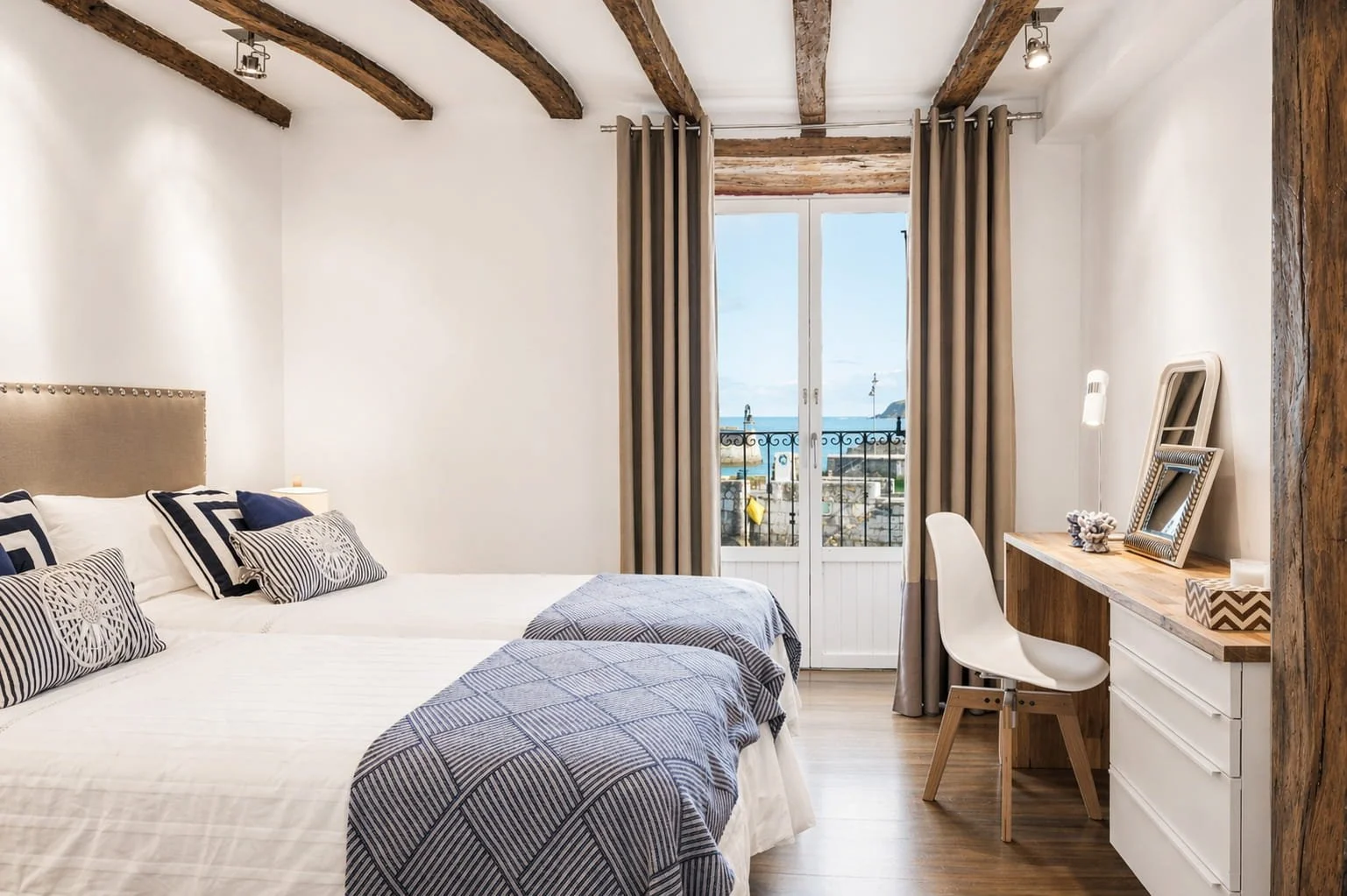 Dormitorio con vistas al mar en Mundaka con vigas de madera y decoración de estilo rústico costero