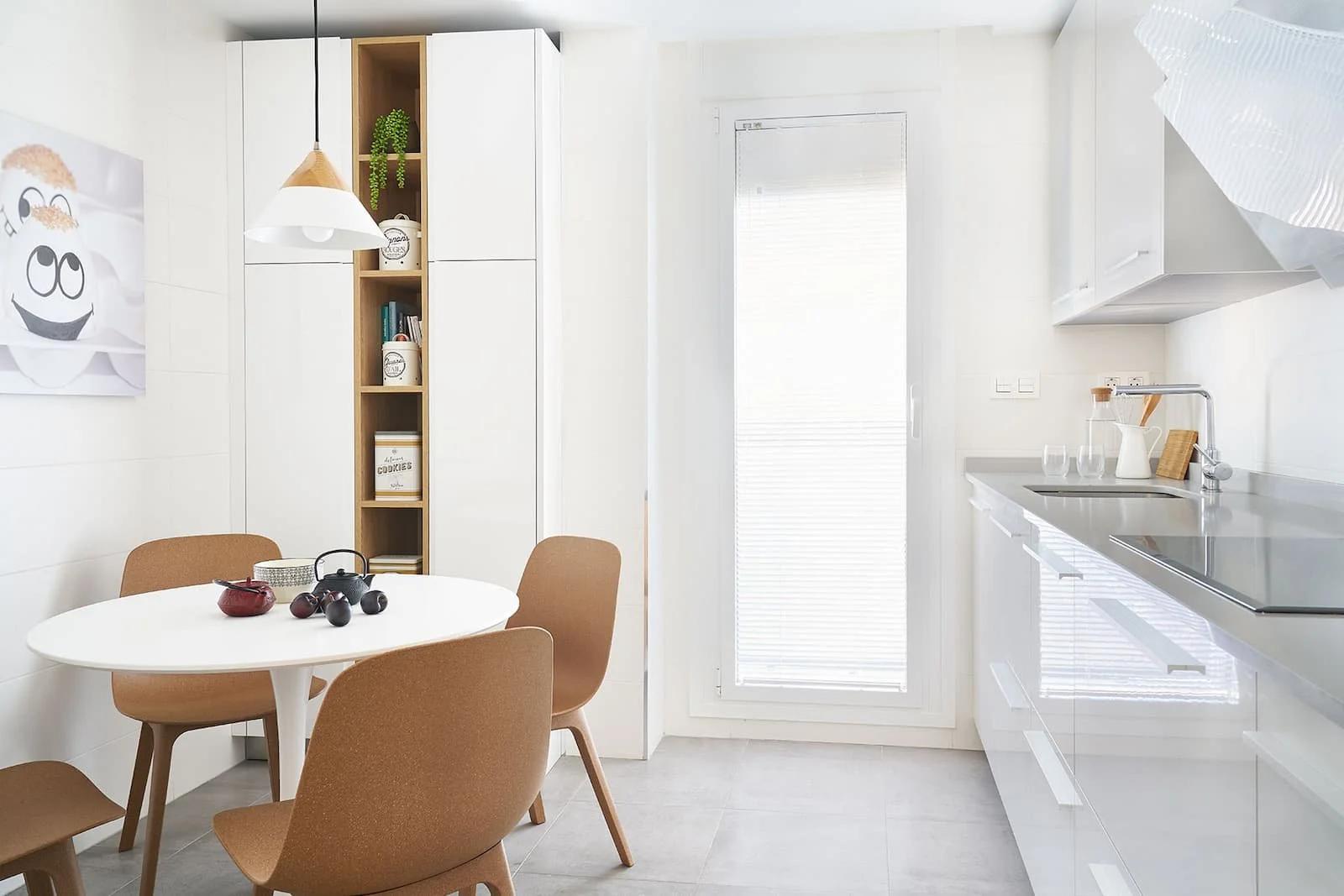Cocina moderna con zona de comedor en vivienda en Urduliz Bizkaia con mobiliario blanco y mesa redonda, proyecto de interiorismo.