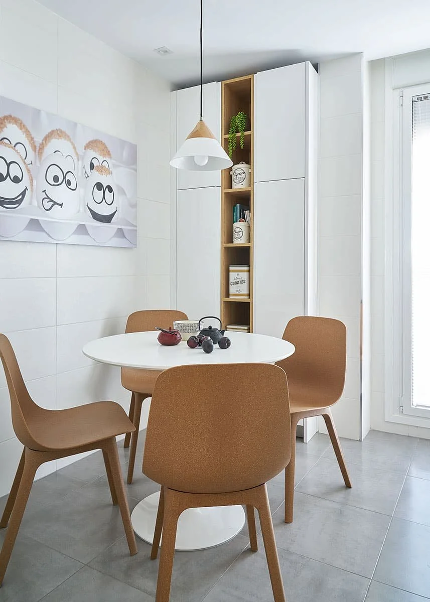 Comedor integrado en cocina moderna con mesa redonda y sillas de madera en vivienda de Urduliz Bizkaia. Proyecto de interiorismo y estilismo.
